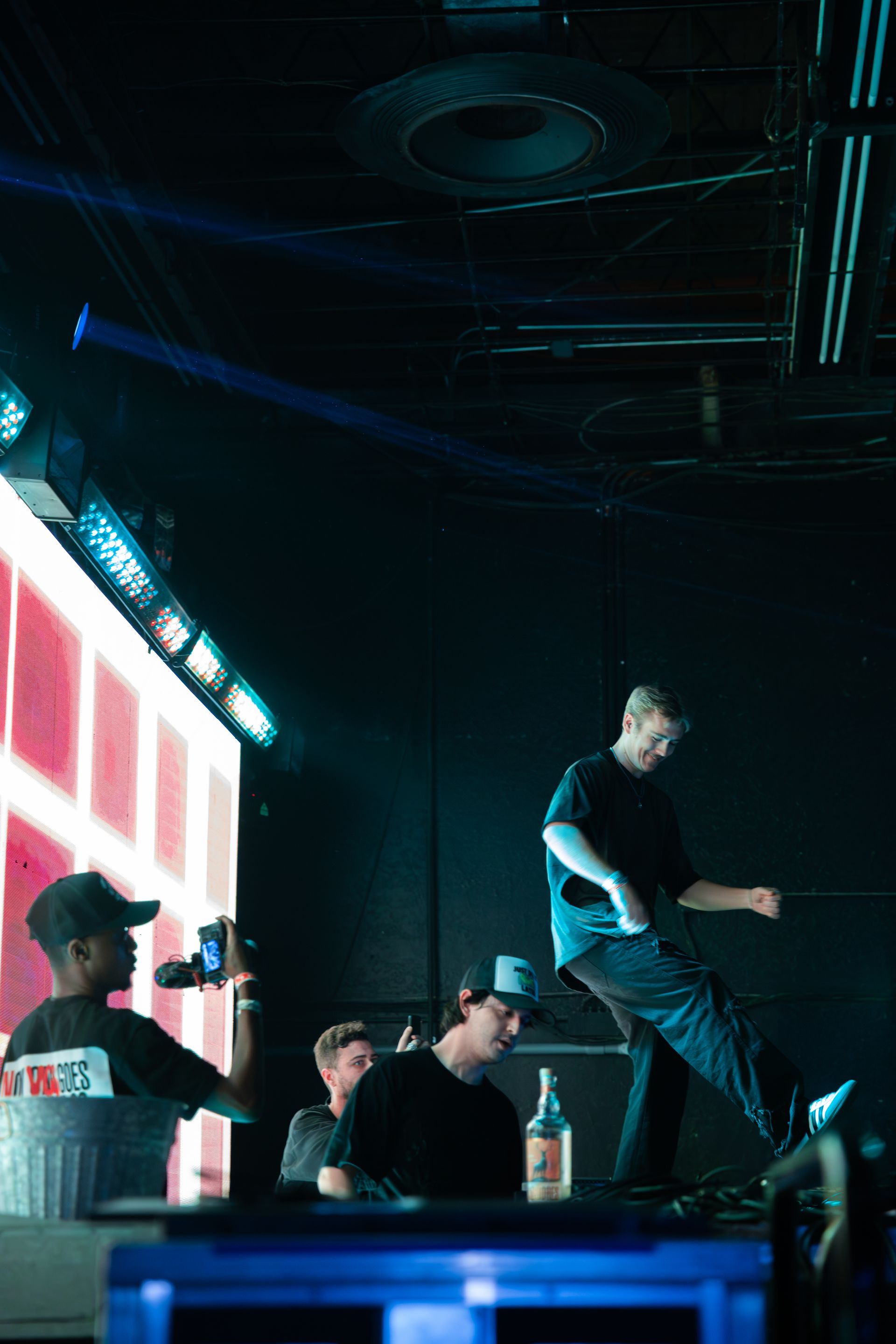 A group of men are dancing on a stage in a dark room.