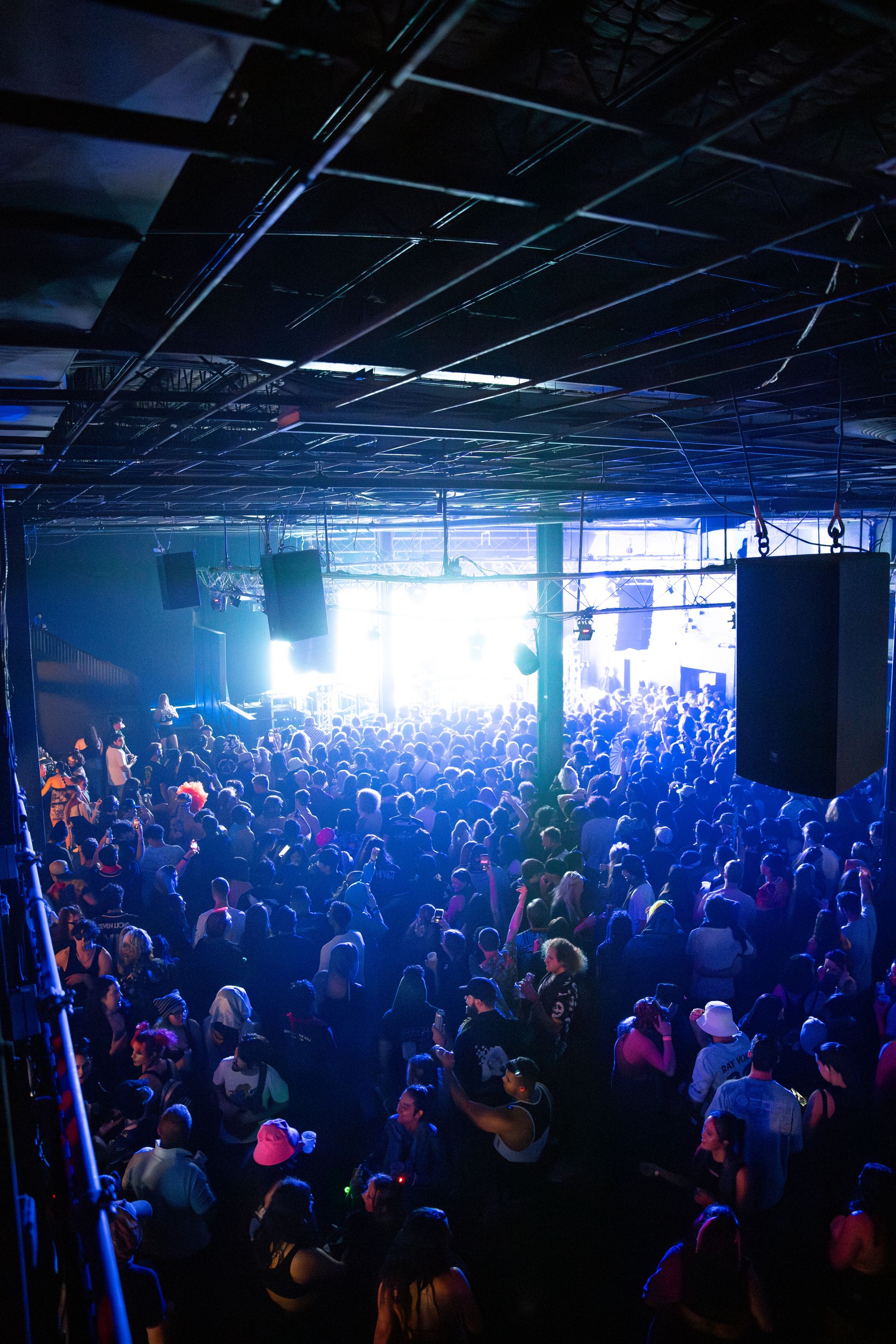 A large crowd of people are gathered in a dark room at a concert.