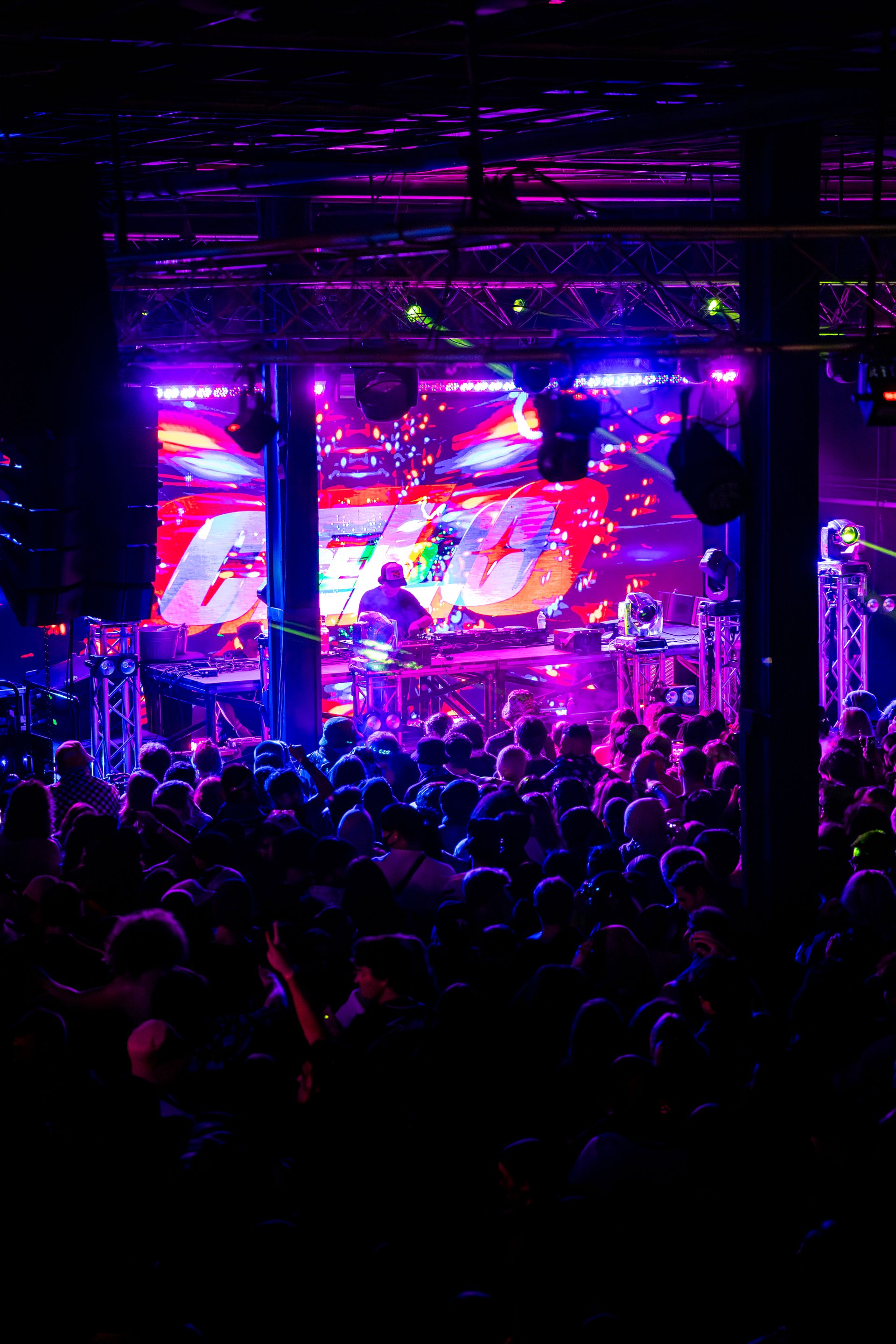 A crowd of people are standing in front of a stage at a concert.
