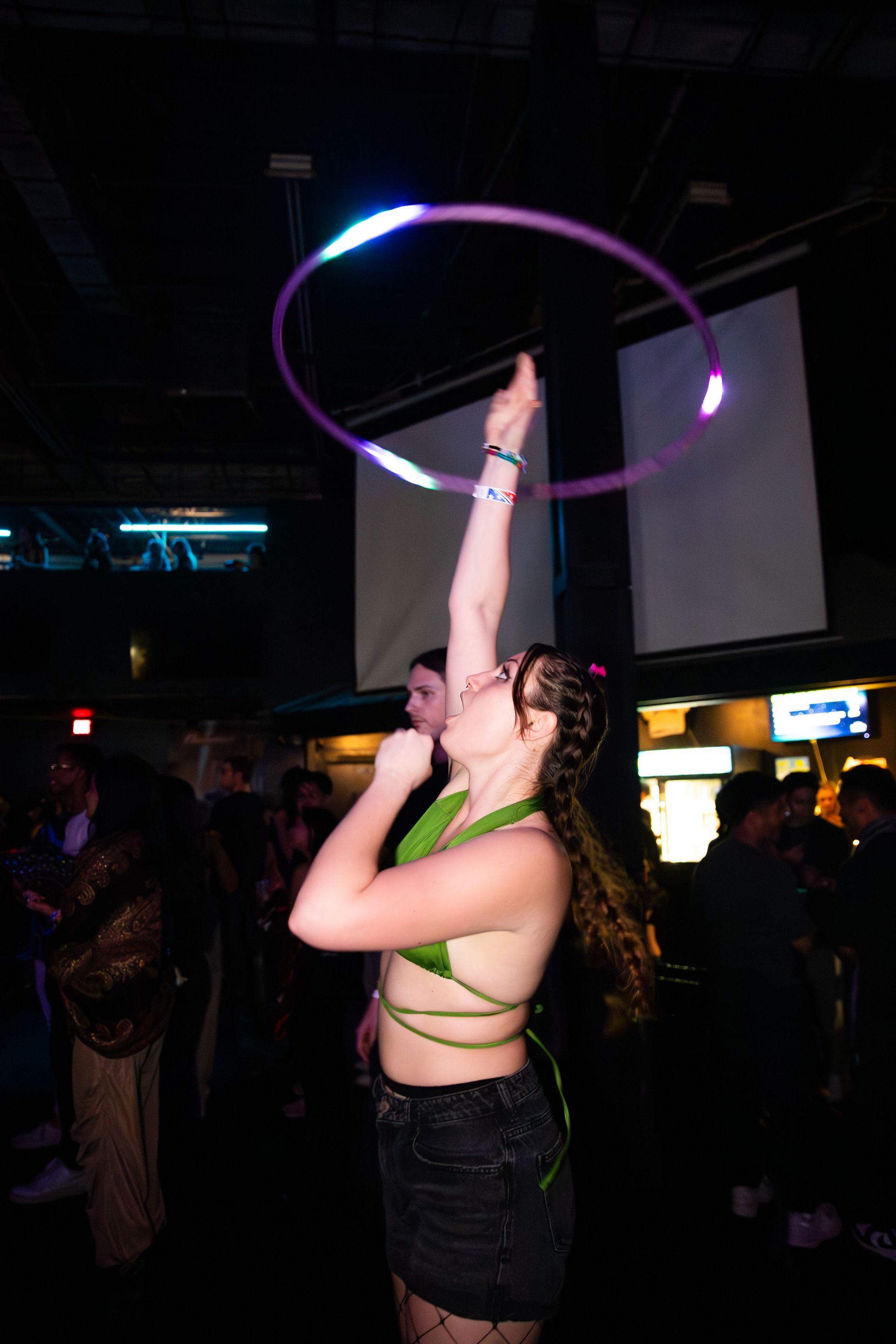 A woman is playing with a hula hoop in a dark room.