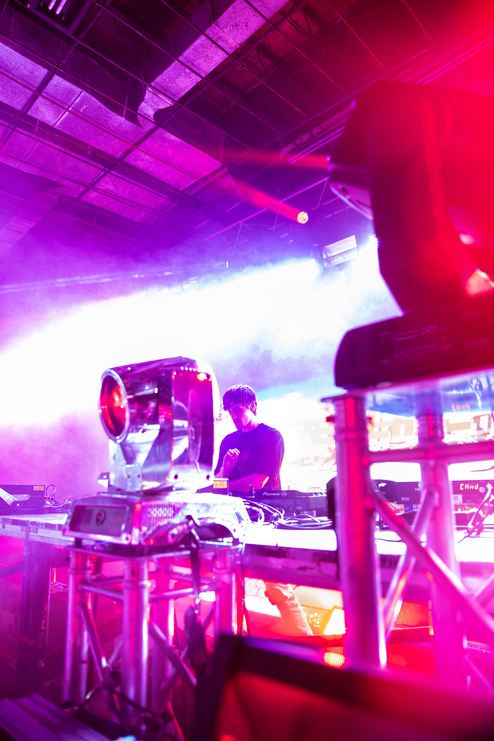 A man is playing a dj set in a dark room with purple lights