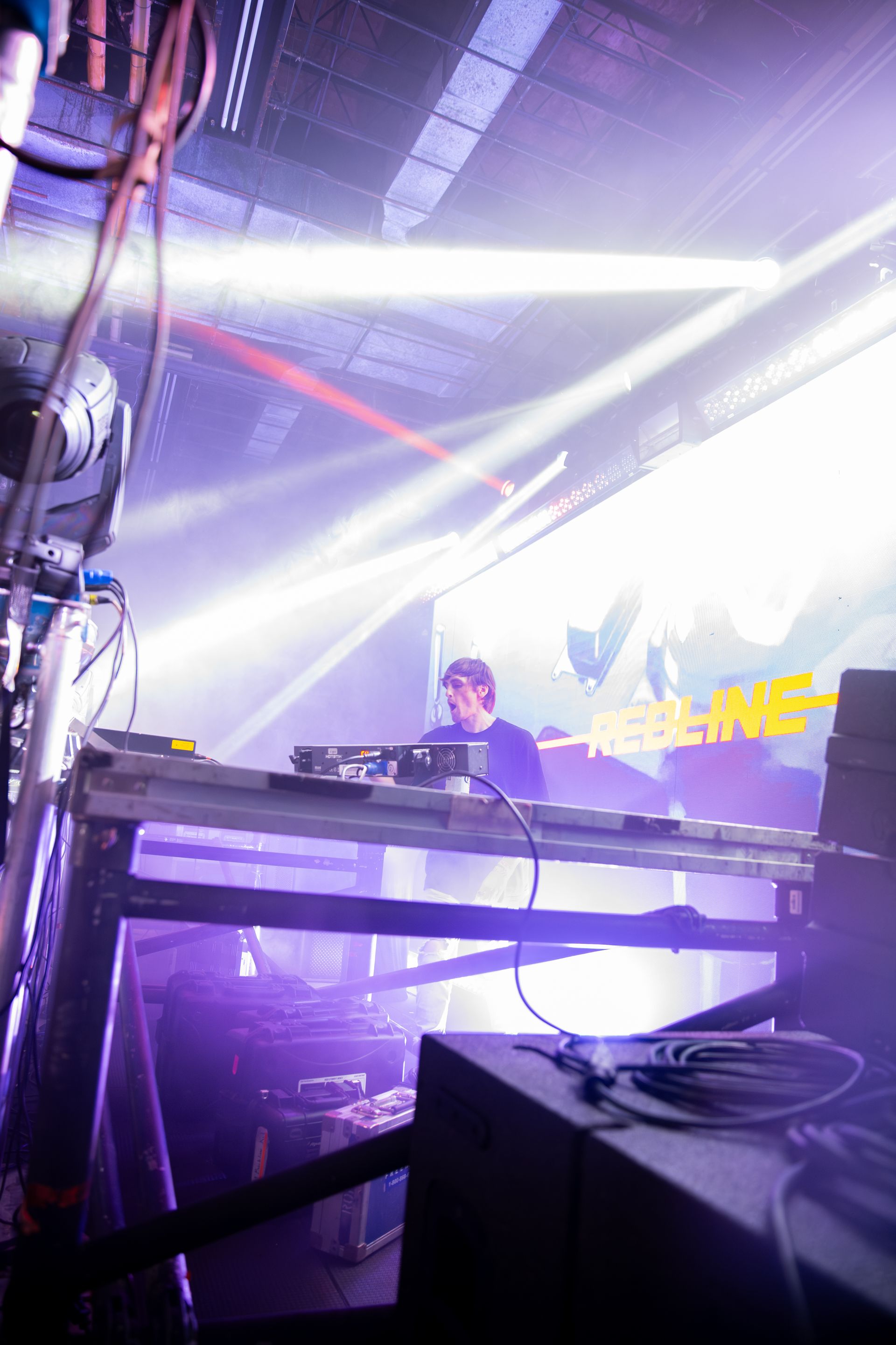 A man is playing a dj set in a dark room with purple lights.