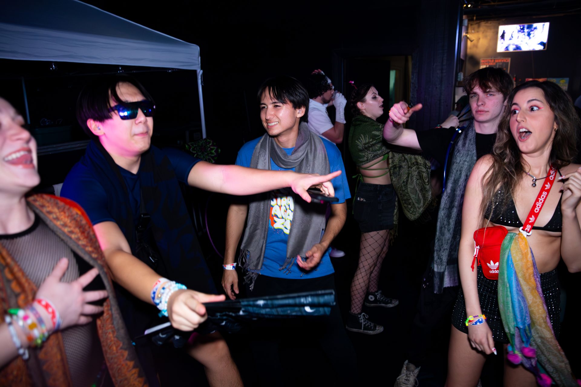 A group of people are dancing in a dark room.