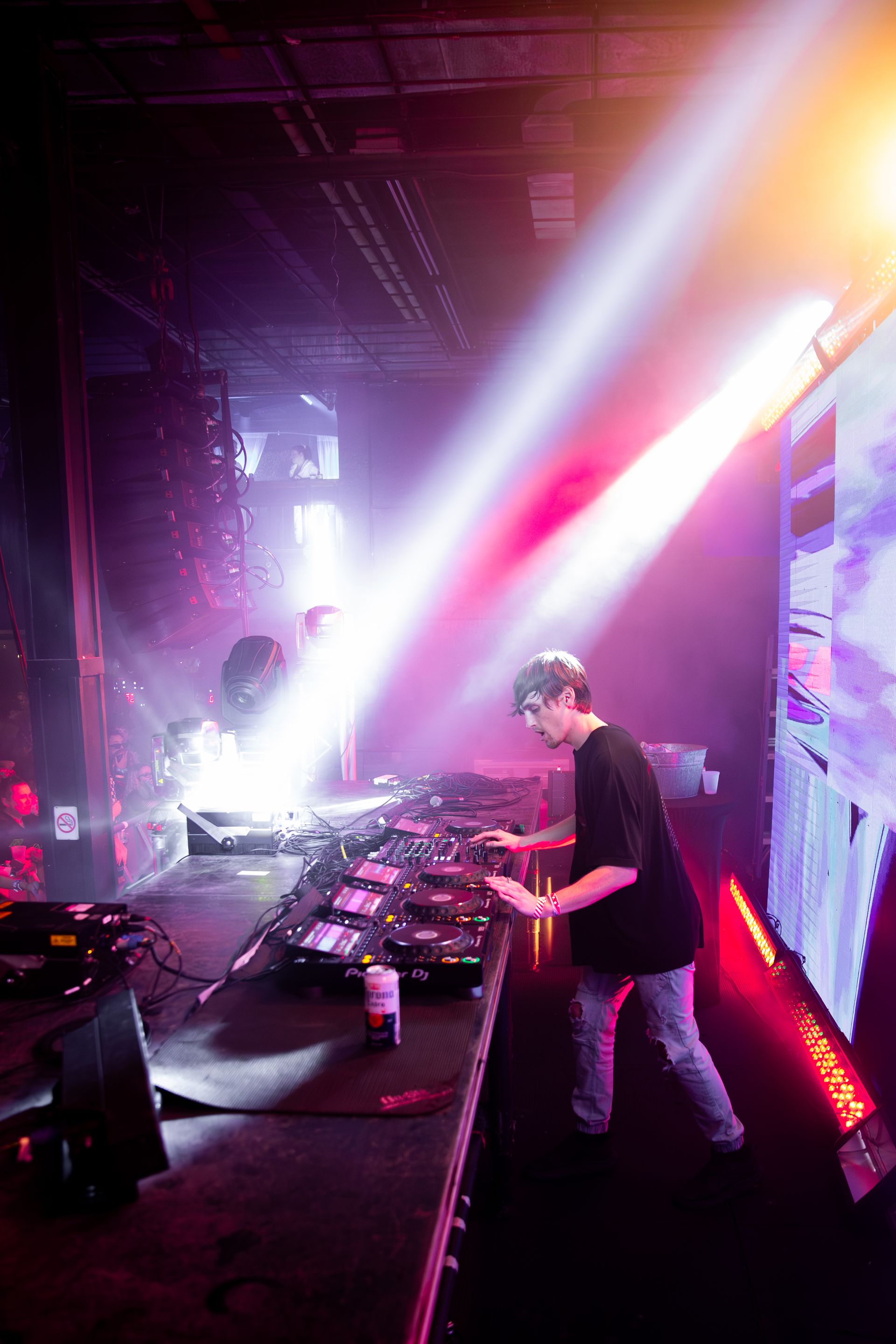 A man is playing a dj set on a stage in a dark room.