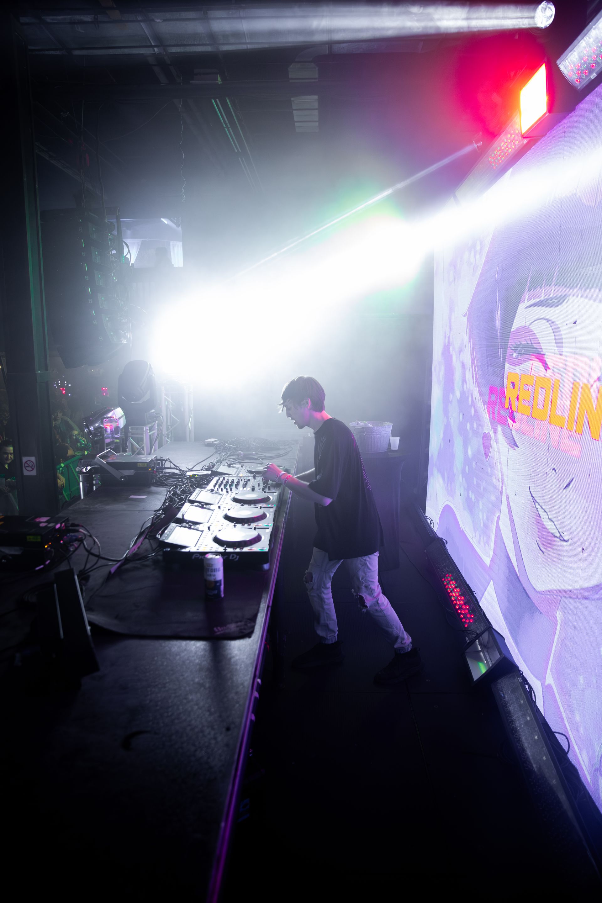 A man is playing a dj set on a stage in a dark room.
