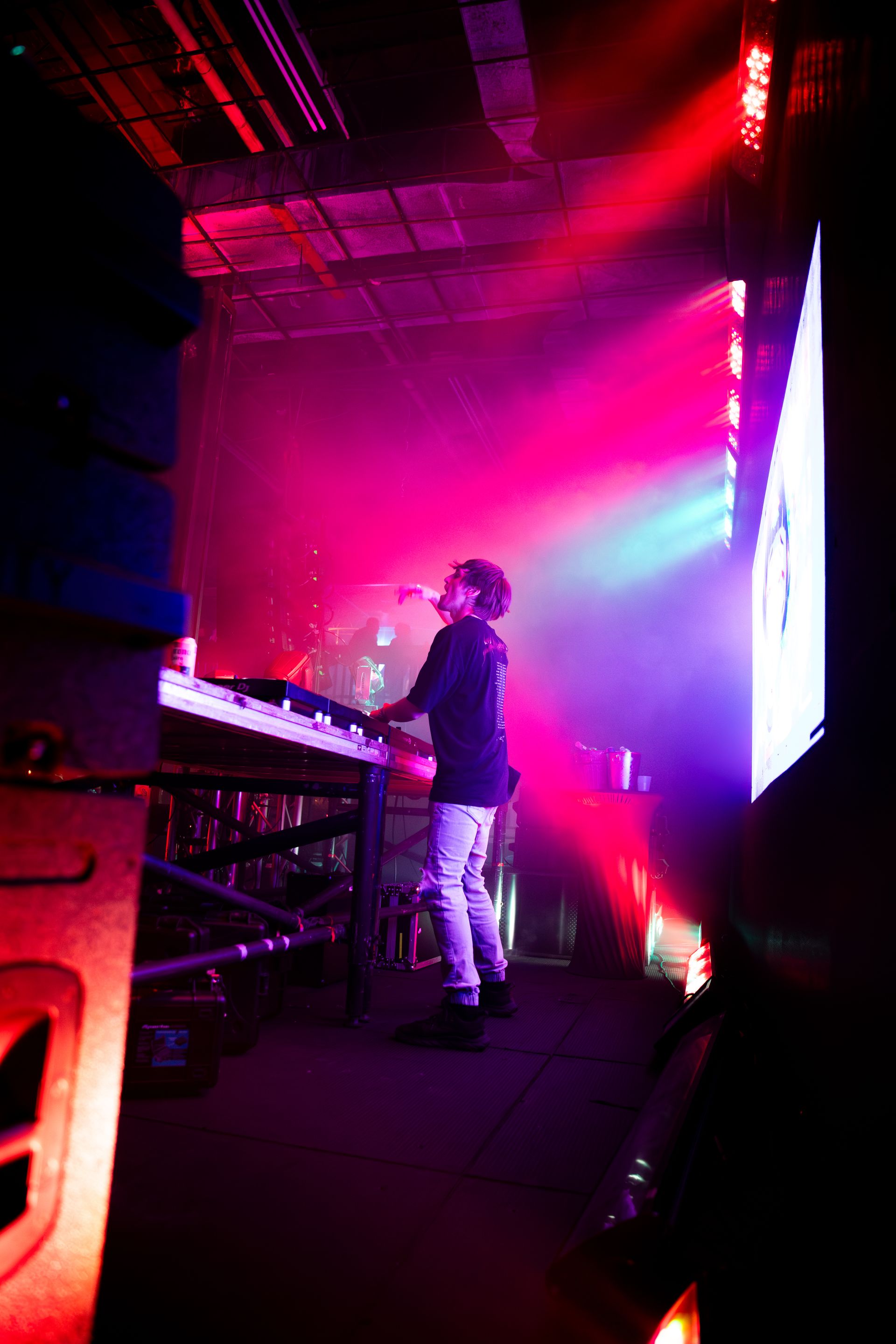 A man is playing a keyboard on a stage in front of a large screen.