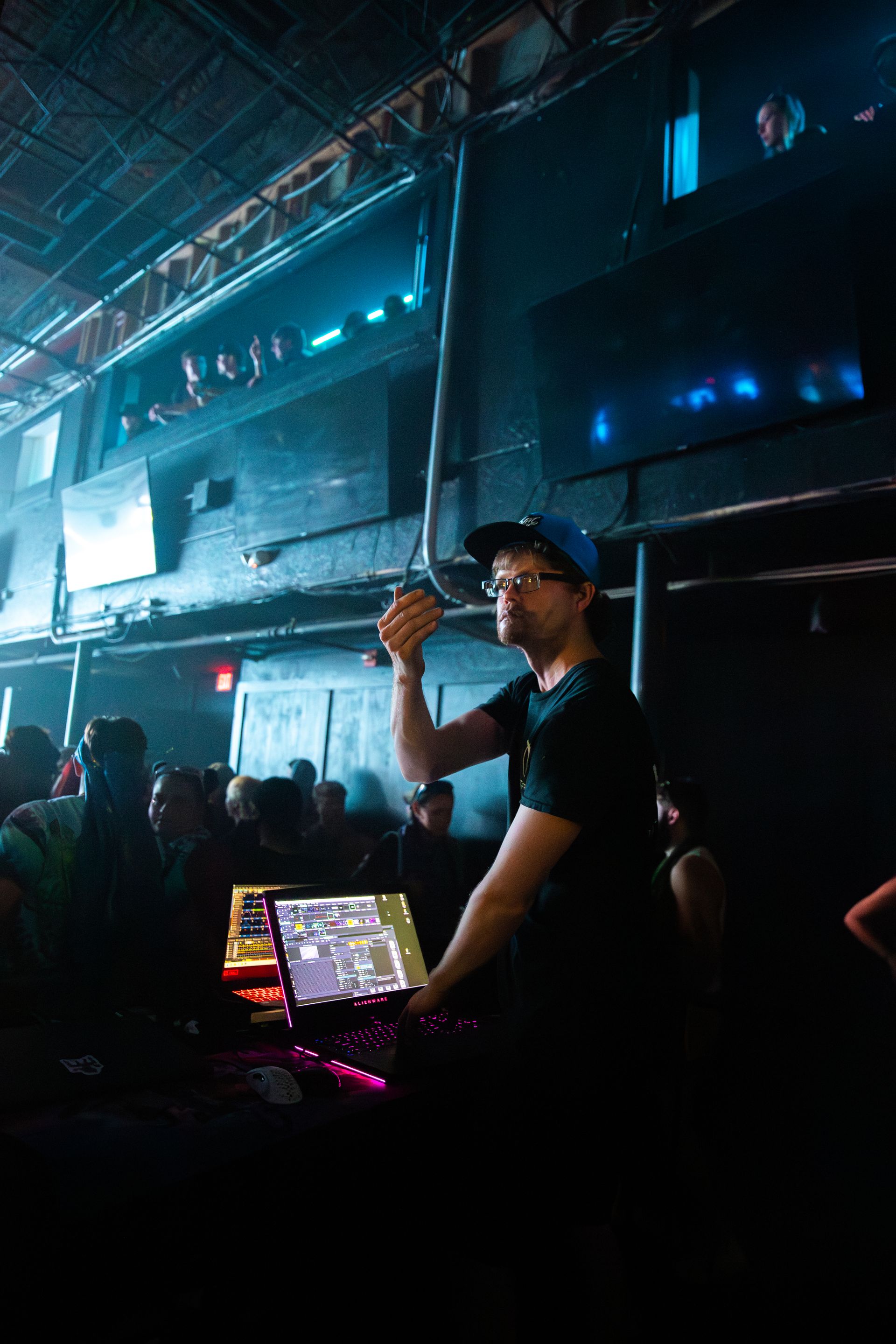 A man is standing in front of a computer in a dark room.