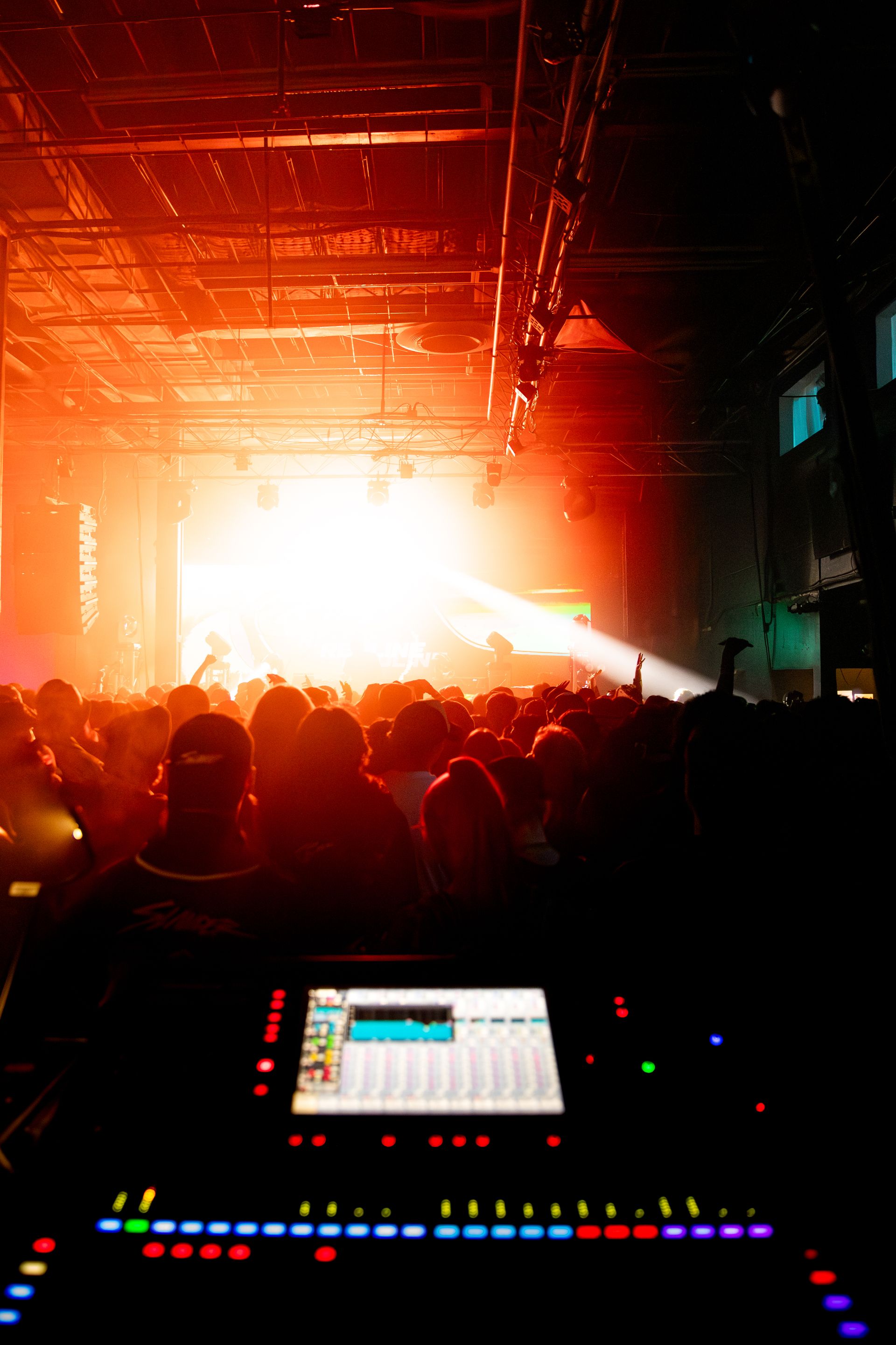 A crowd of people are watching a concert in a dark room.