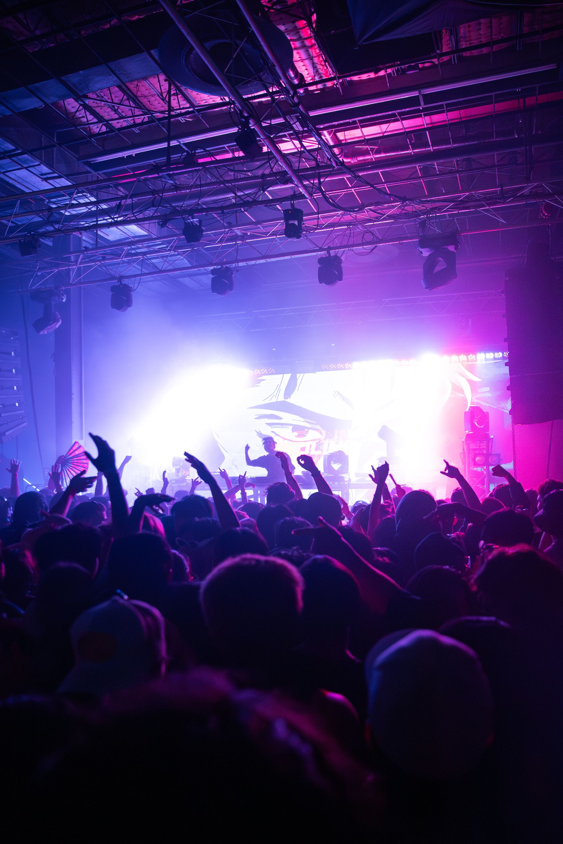 A crowd of people are standing in front of a stage at a concert.
