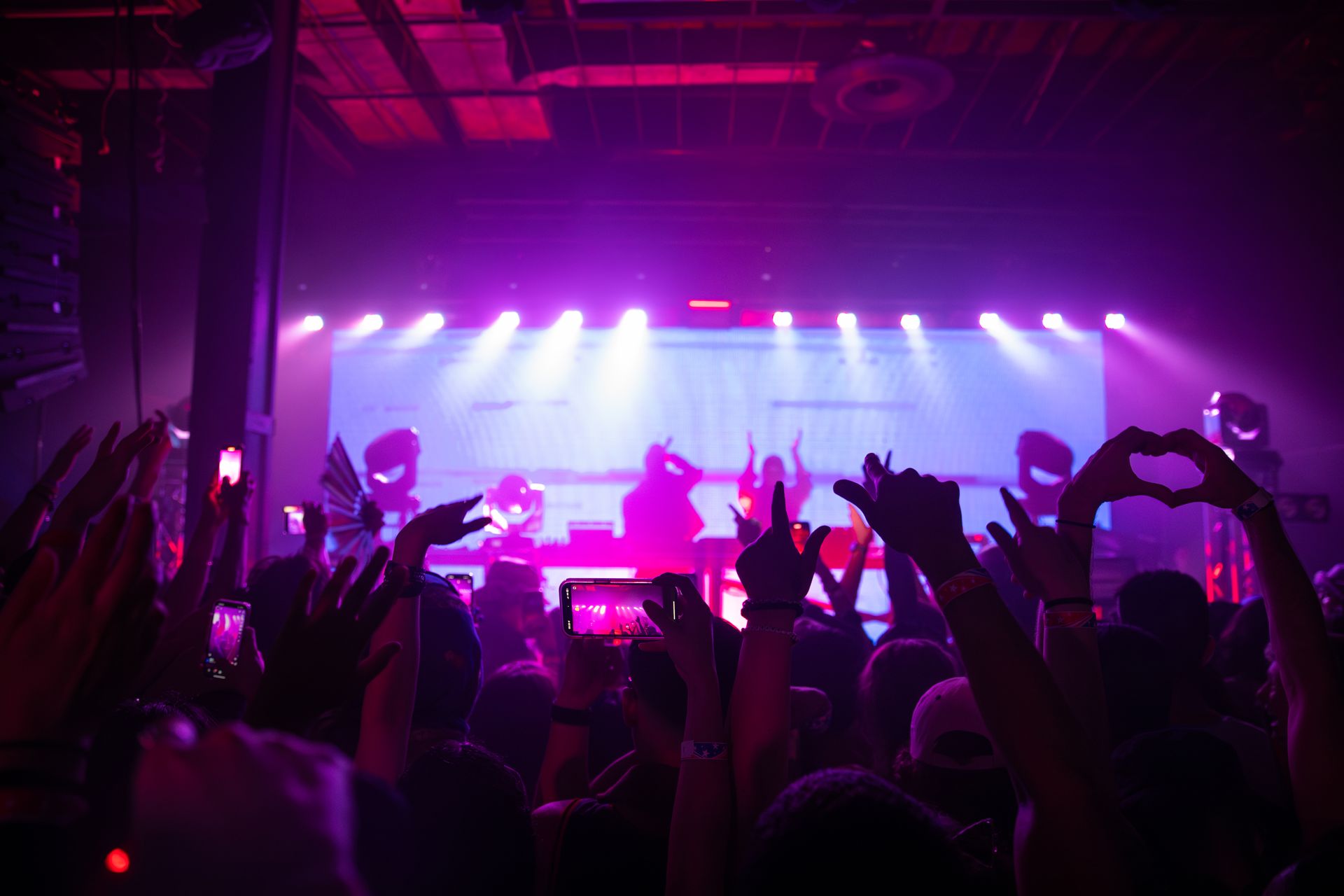 A crowd of people are standing in front of a stage at a concert.