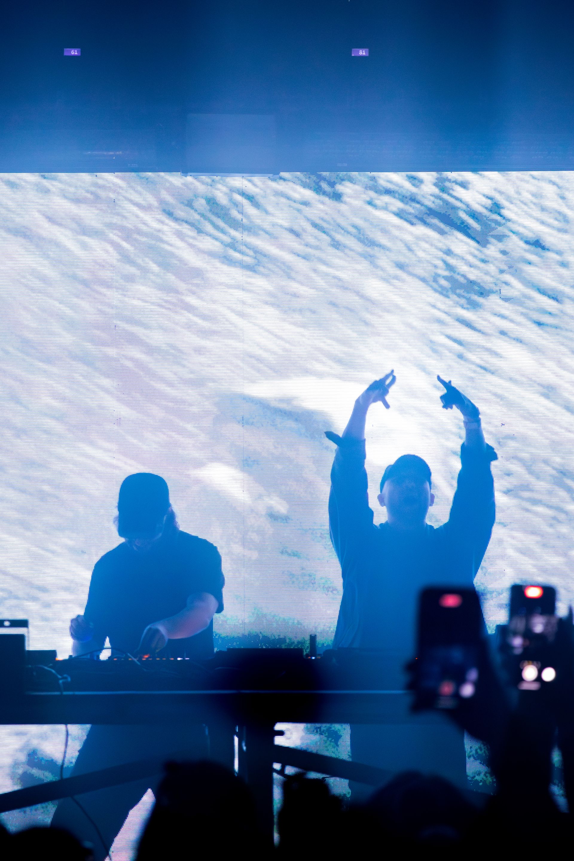 A couple of men are standing on a stage with their arms in the air.