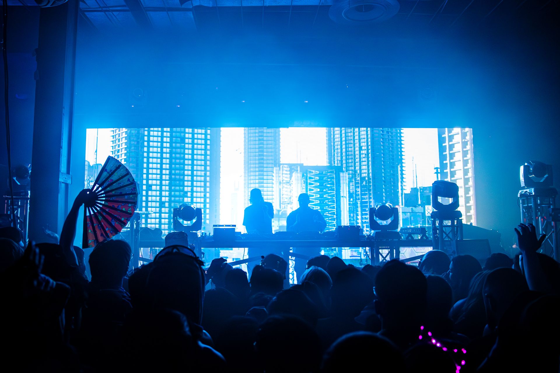 A crowd of people are watching a dj perform on stage.