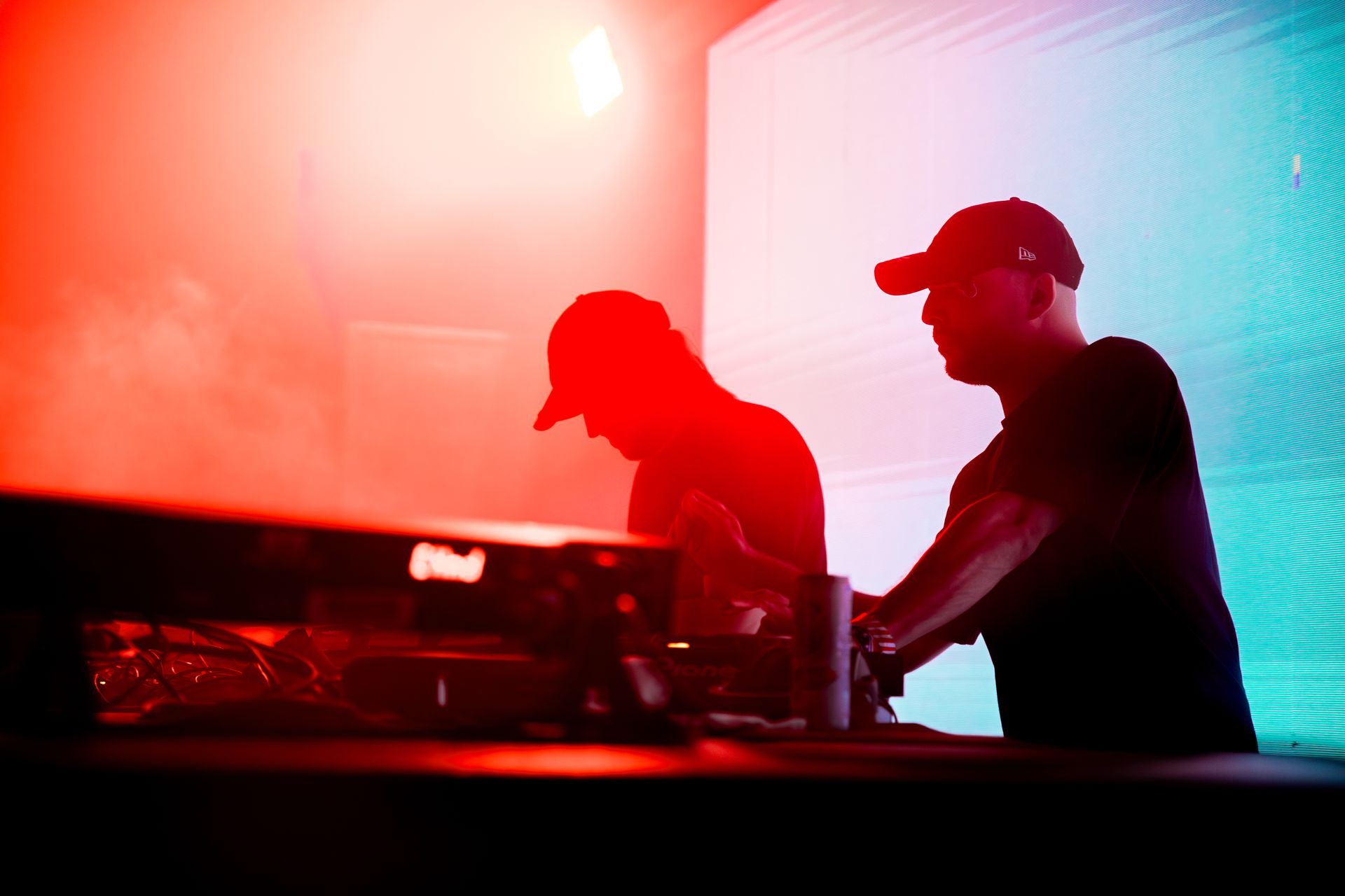 Two men are playing music on a stage with red and blue lights behind them