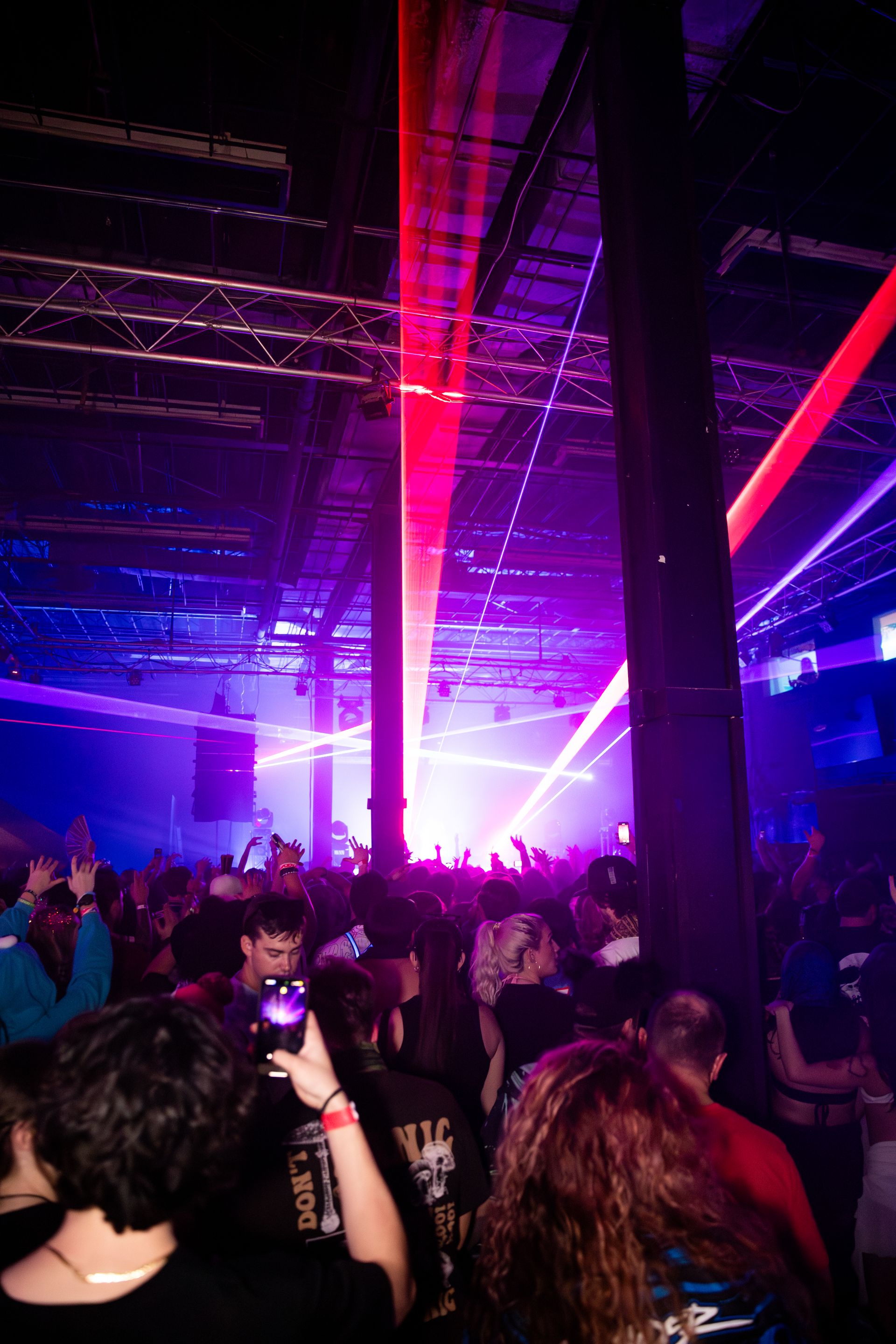 A crowd of people are standing in a dark room at a concert.