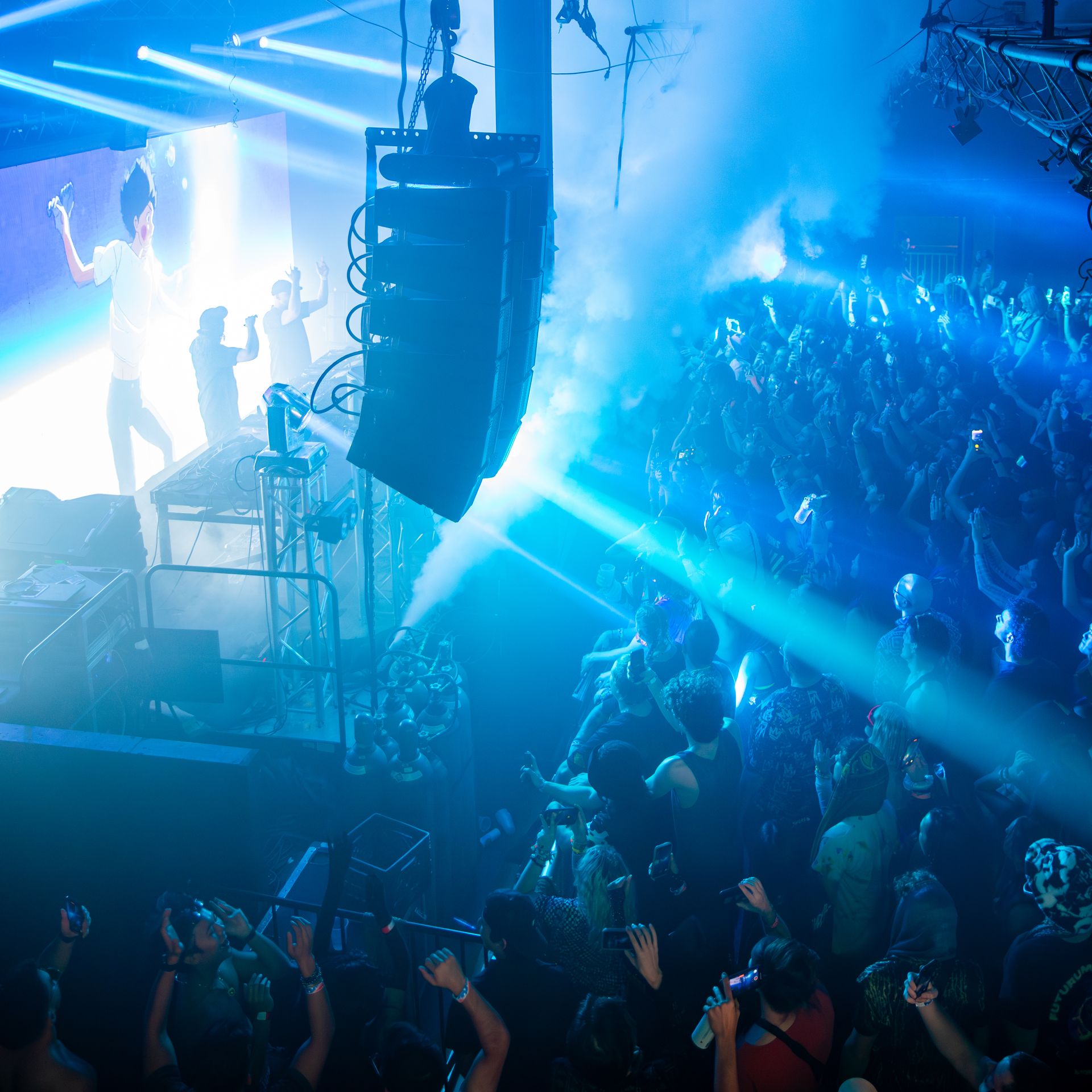 A crowd of people are standing in a dark room at a concert.