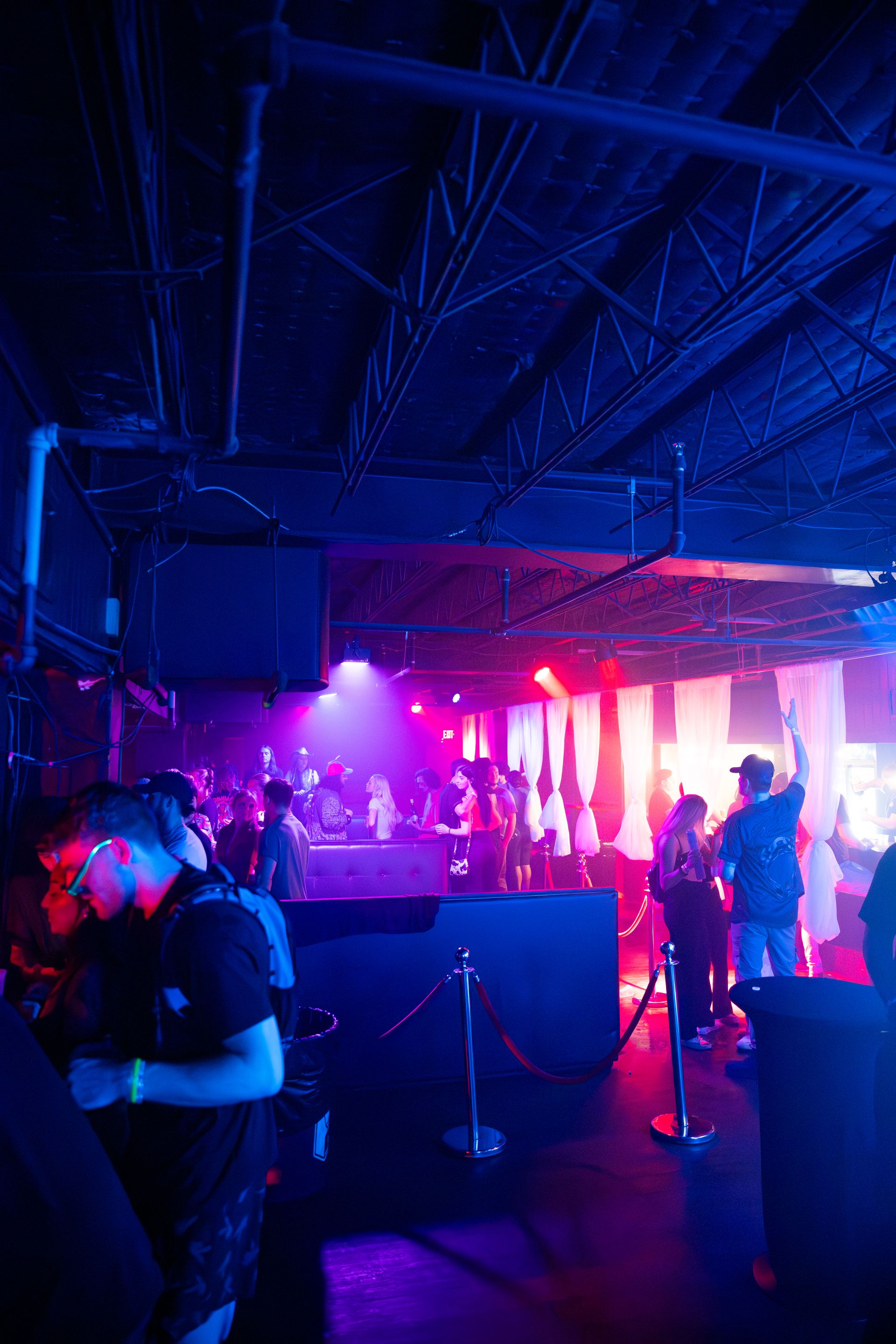 A group of people are standing in a dark room with blue and purple lights.