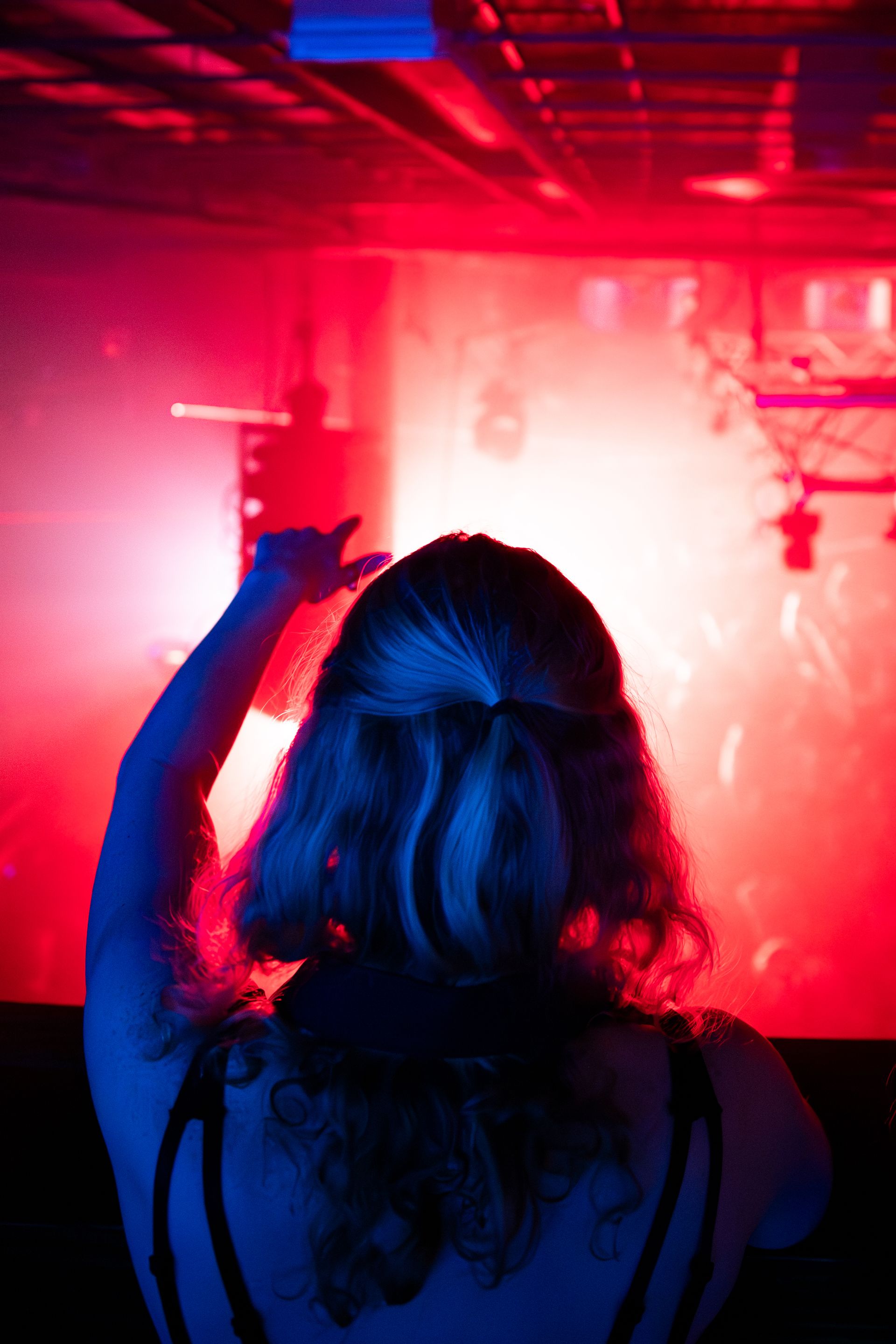 A woman is dancing in a dark room with red and blue lights.