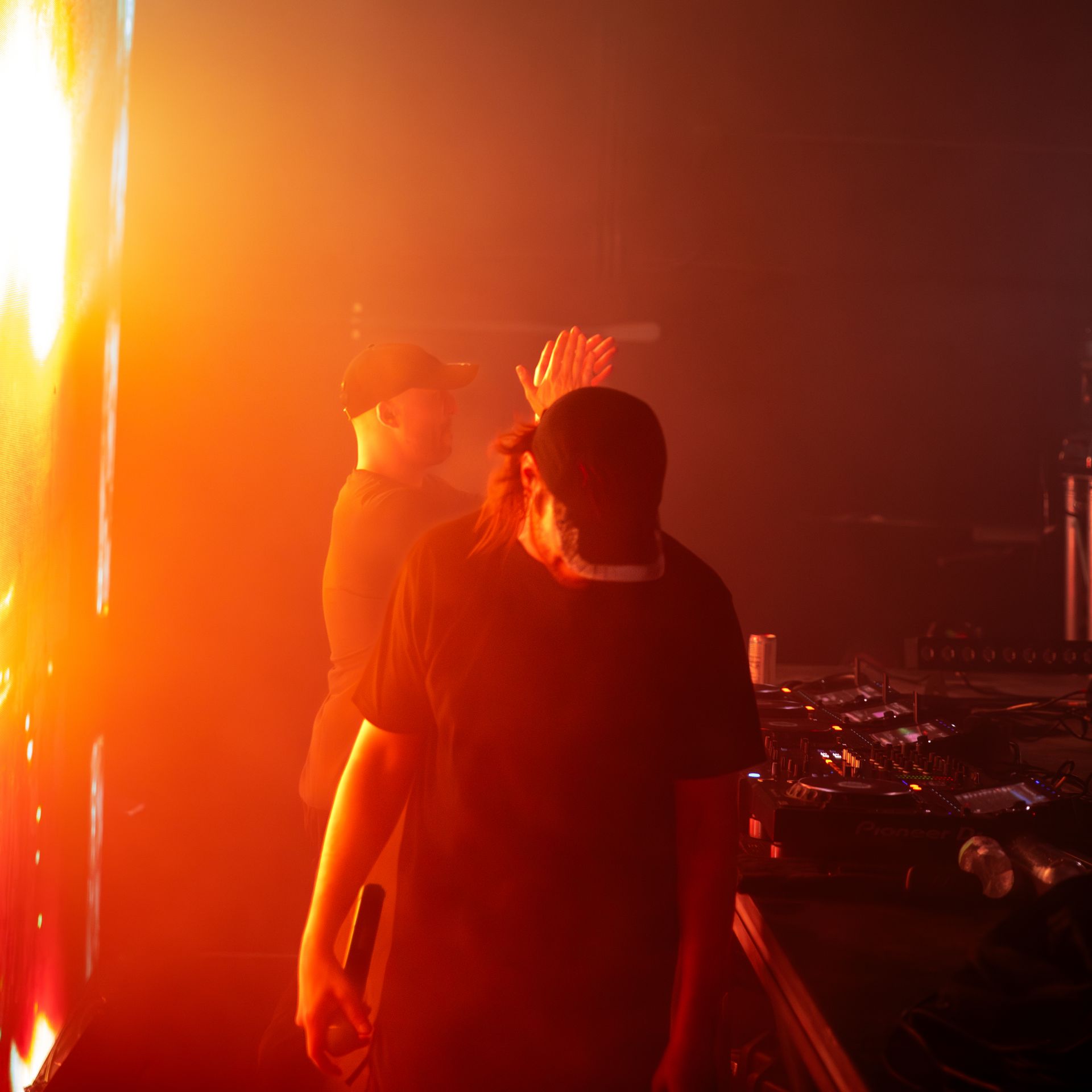 Two men are standing in front of a fire in a dark room