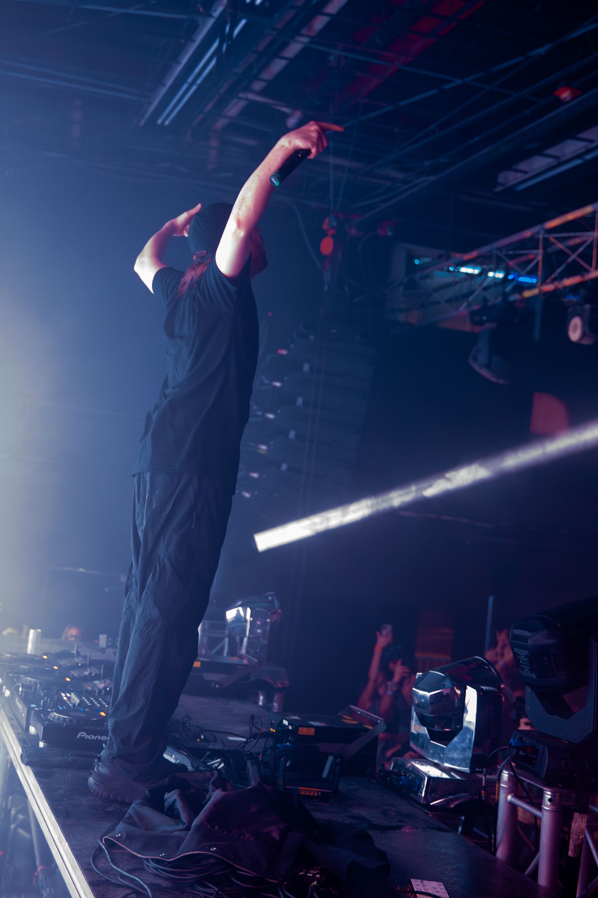 A man is singing into a microphone on a stage in a dark room.