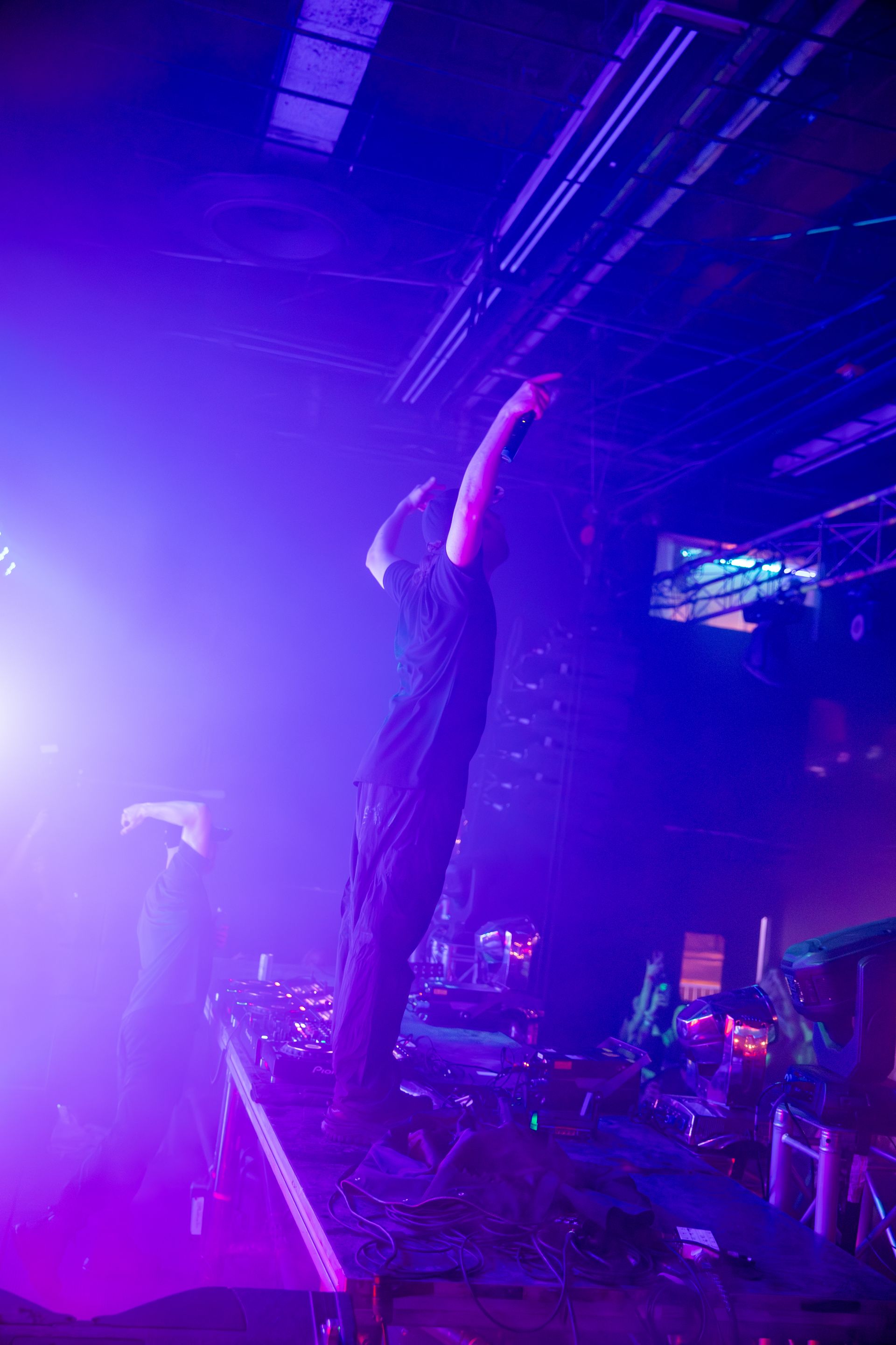 A man is standing on a stage in a dark room with purple lights.