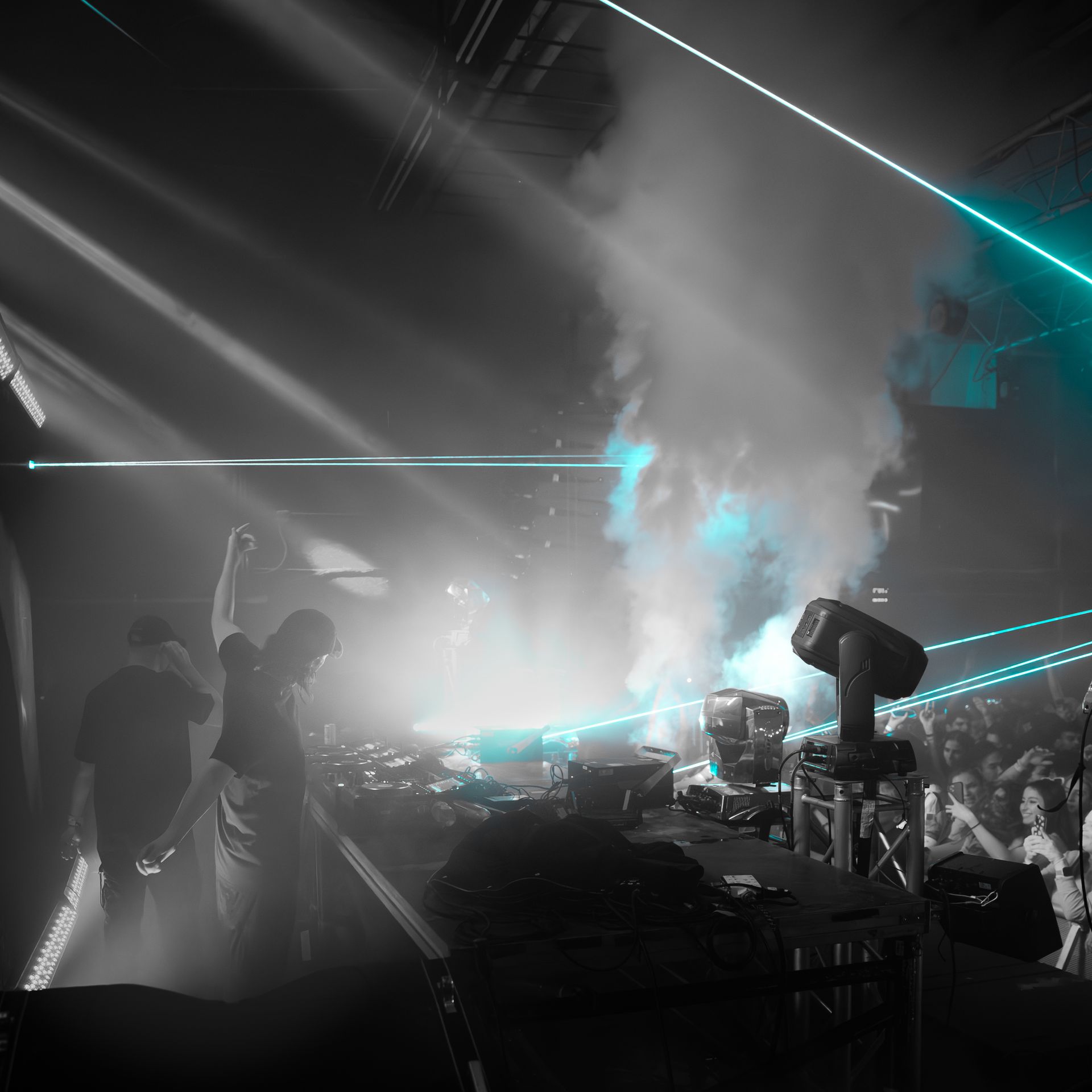 A group of people are dancing in a dark room with smoke coming out of the ceiling.