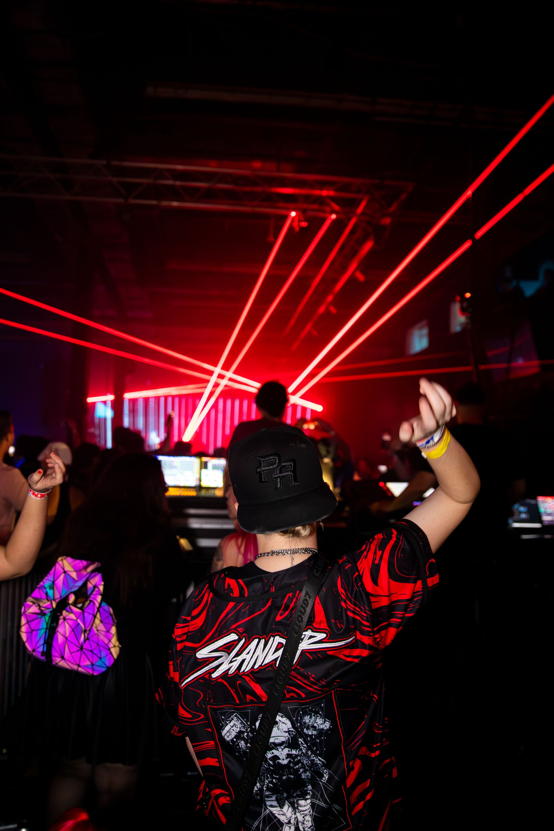 A group of people are dancing in a dark room with red lights.