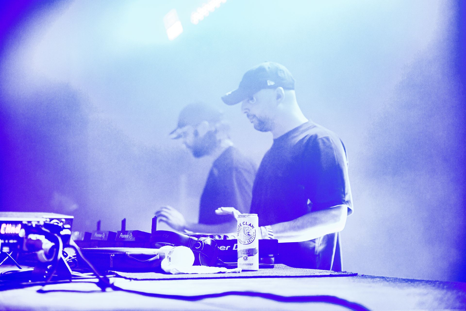 Two men are playing music in a dark room with a blue light behind them