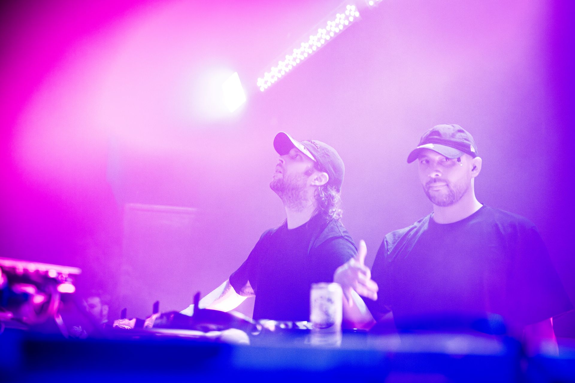 Two men are standing next to each other on a stage in front of a purple light.