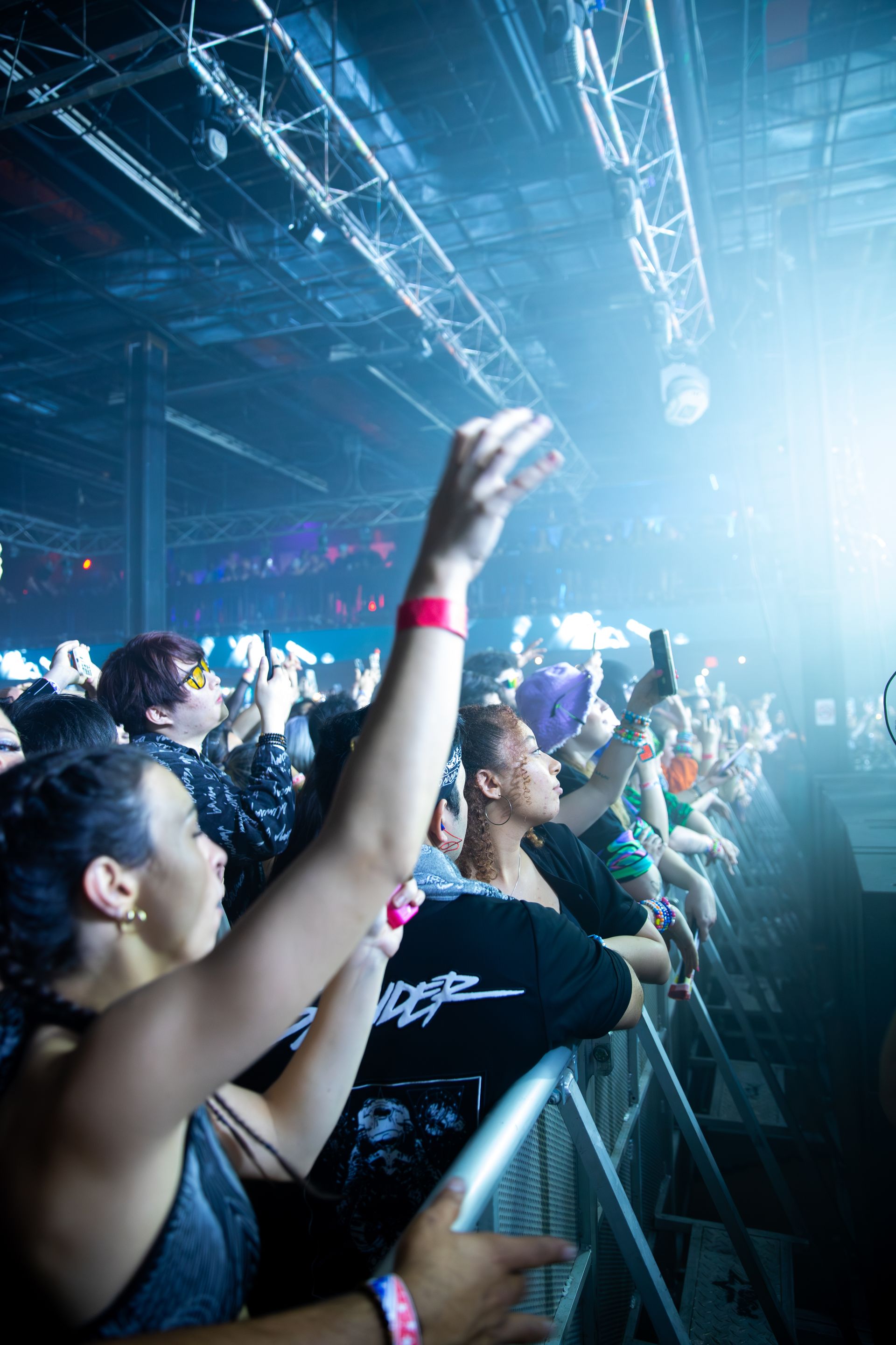 A crowd of people watching a concert with their hands in the air.