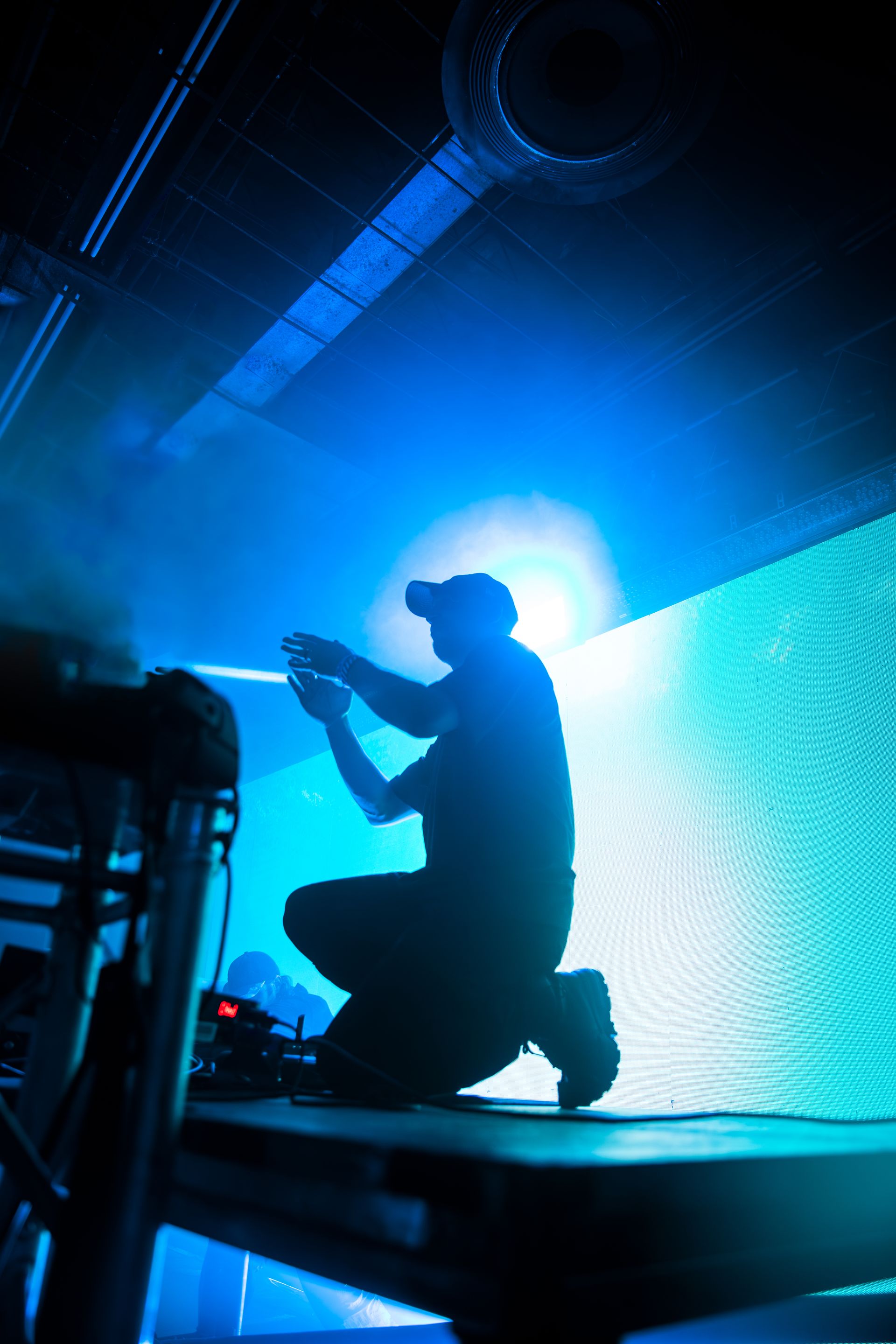 A man is kneeling down on a stage in front of a large screen.