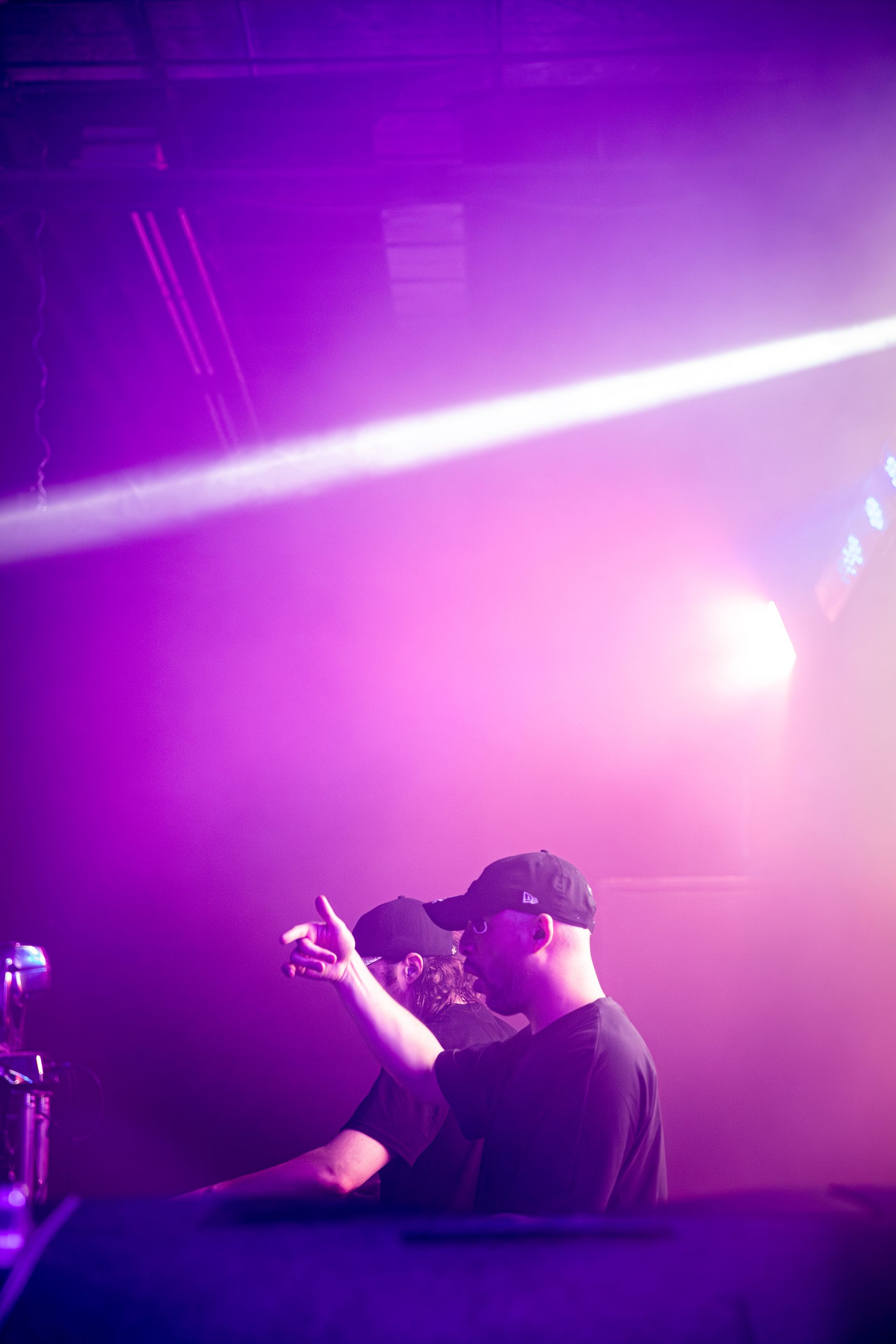 A man is standing in front of a microphone in a dark room with purple lights.