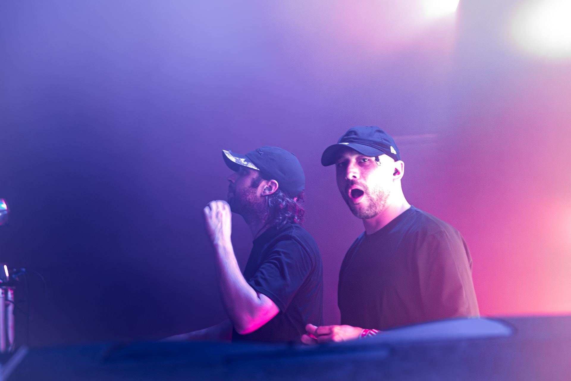 Two men are standing next to each other on a stage in a dark room.