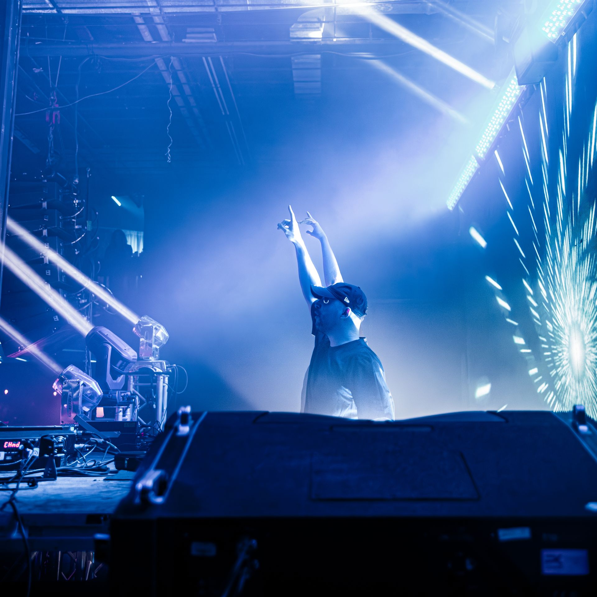 A person standing on a stage with their arms in the air