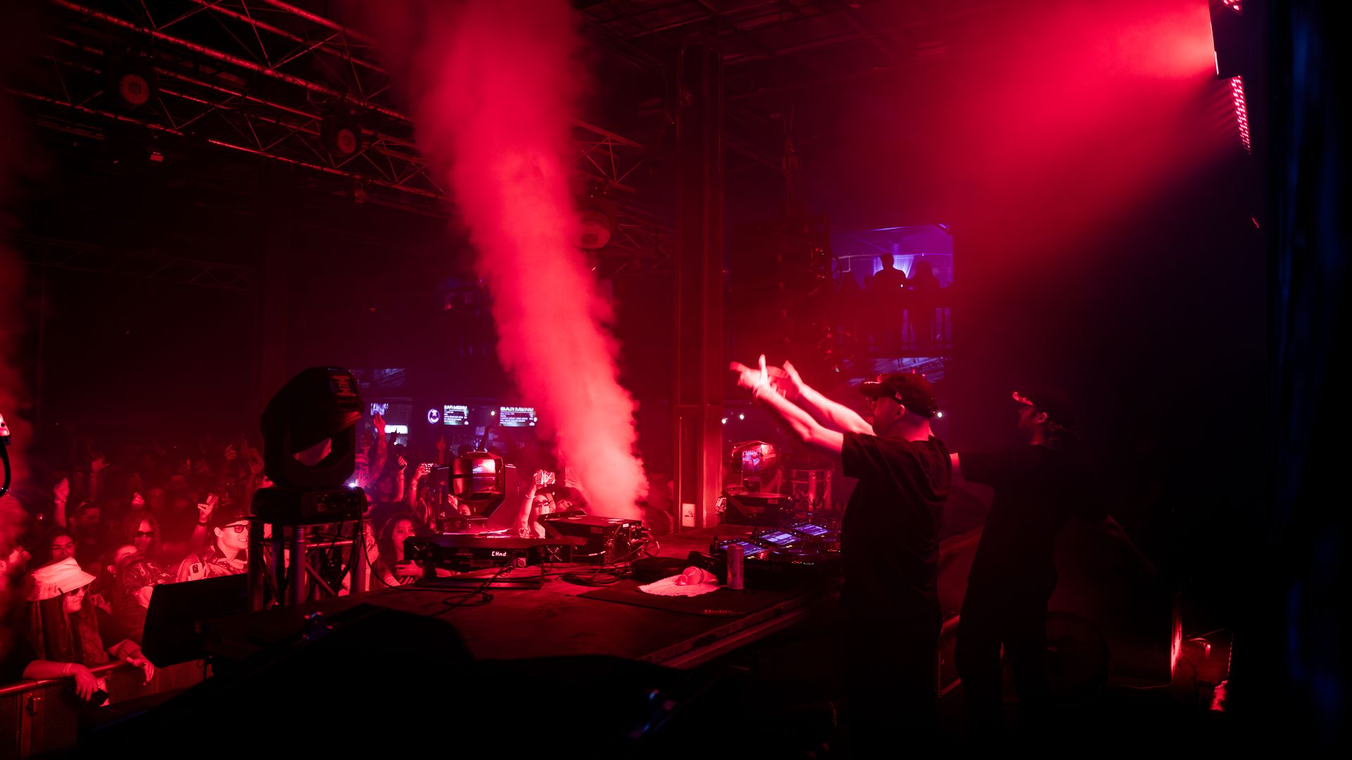 A group of people are standing on a stage in a dark room with red lights.