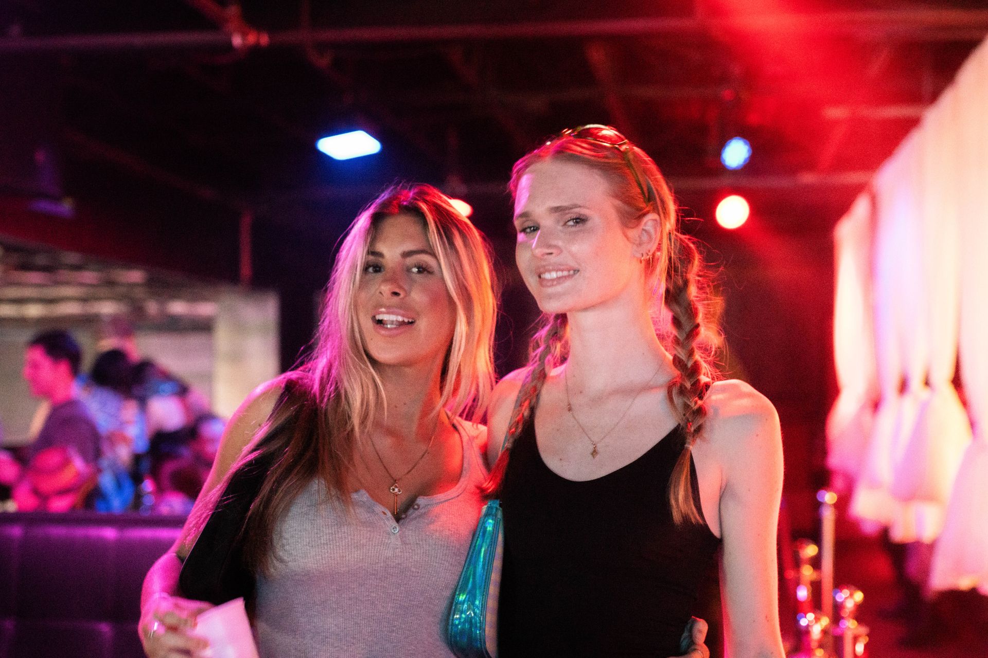 Two women are posing for a picture in a dark room.