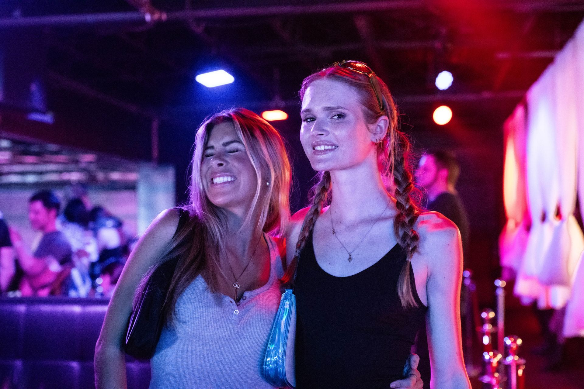 Two women are posing for a picture in a club.