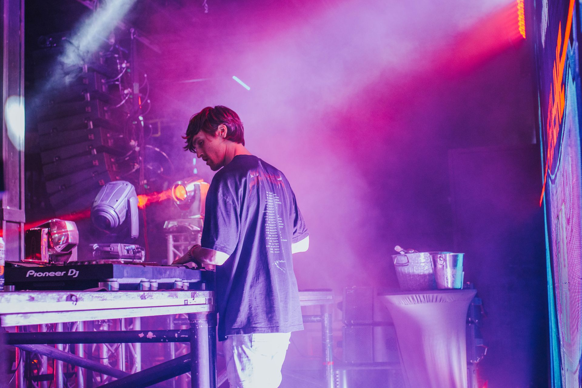 A man is playing a dj set on a stage with purple lights.
