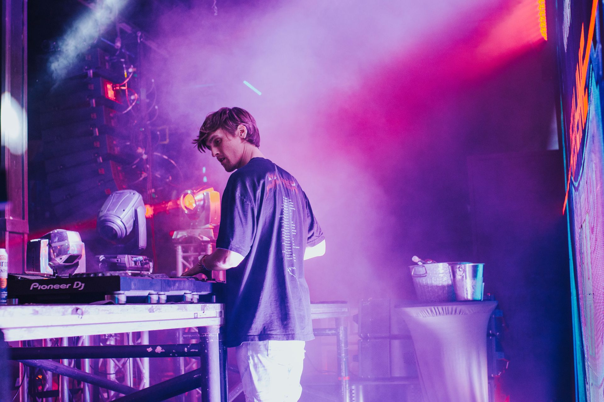A man is playing a dj set on a stage in a club.
