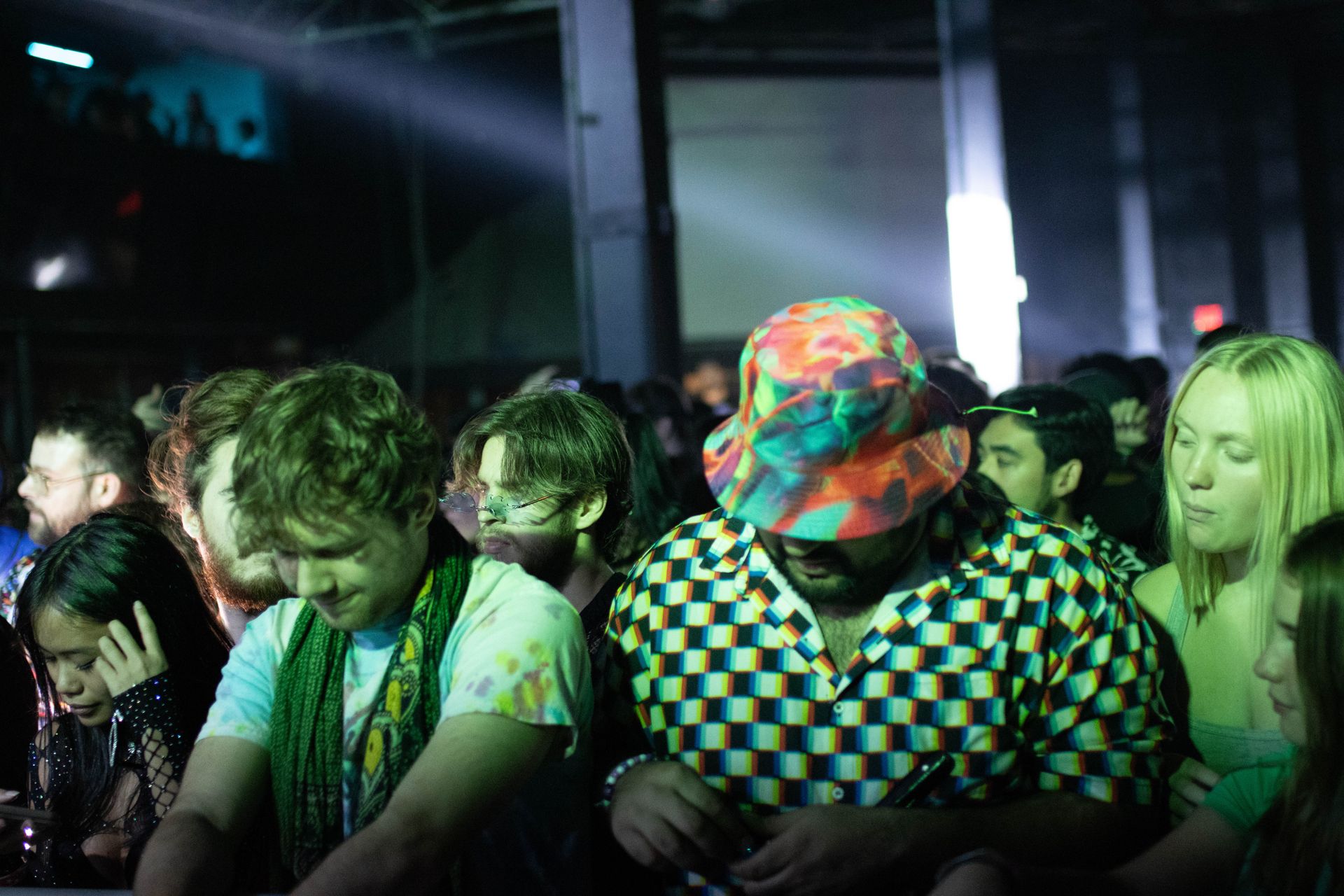 A group of people are standing in a dark room at a party.
