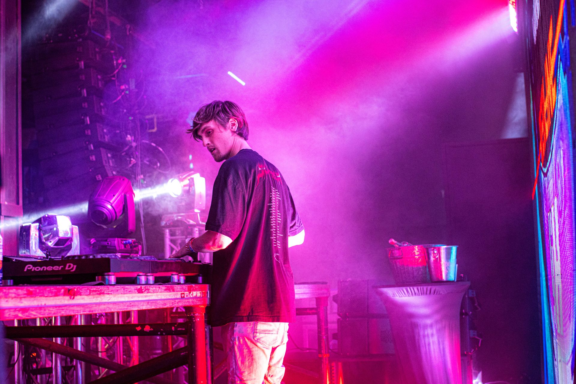 A man is playing a dj set on a stage with purple lights.