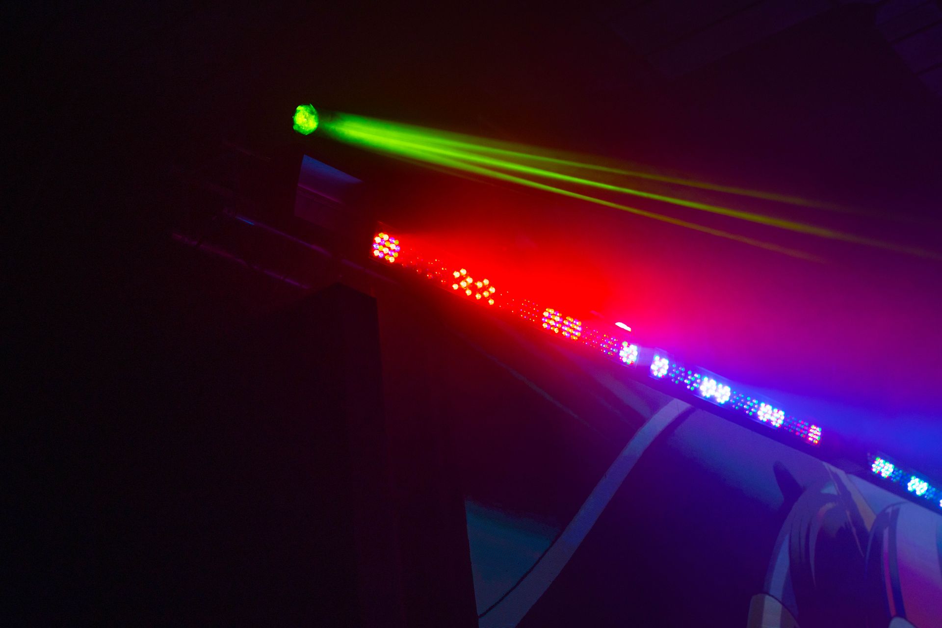 A person is standing in front of a row of colorful lights.