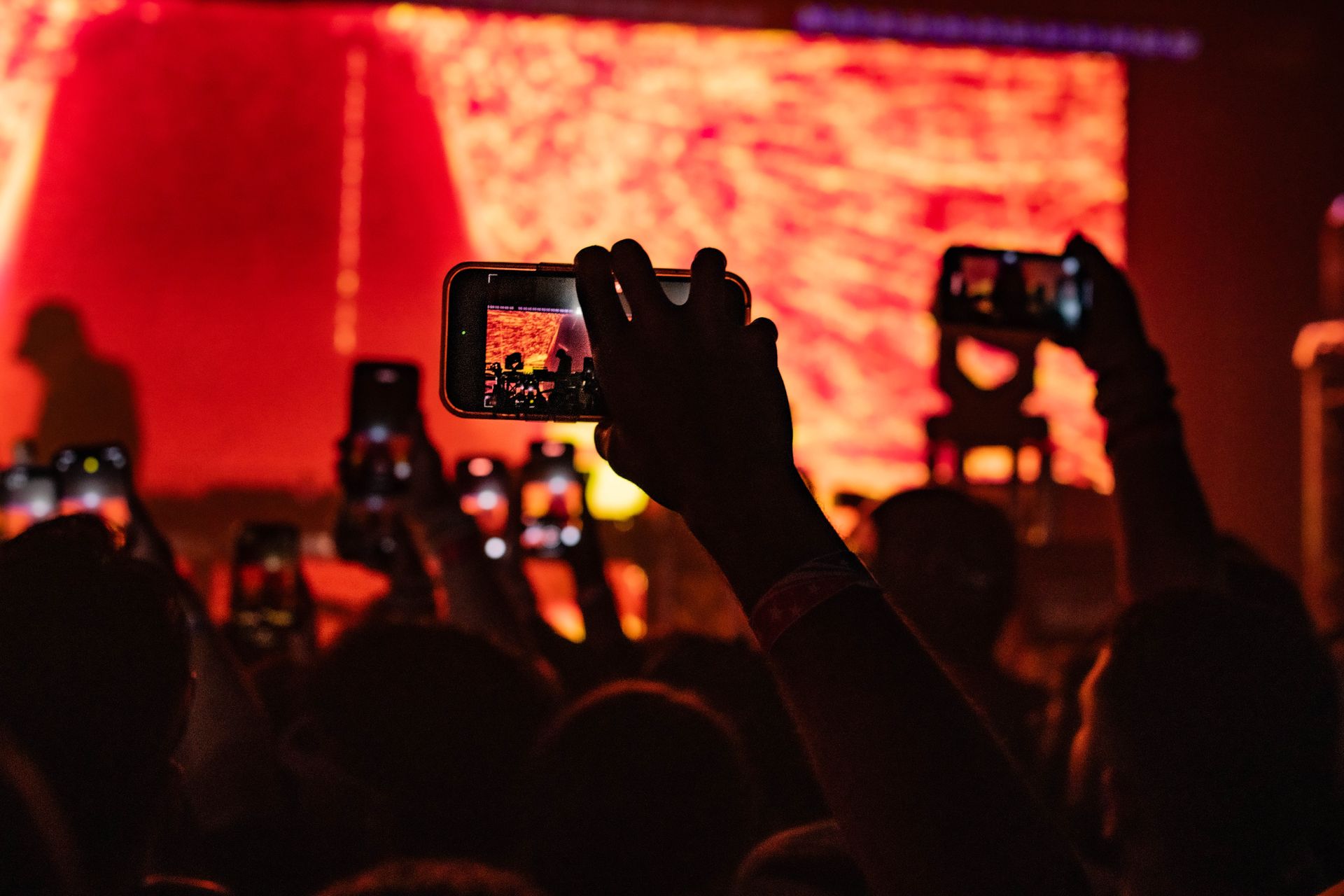 A crowd of people are taking pictures of a concert with their phones.
