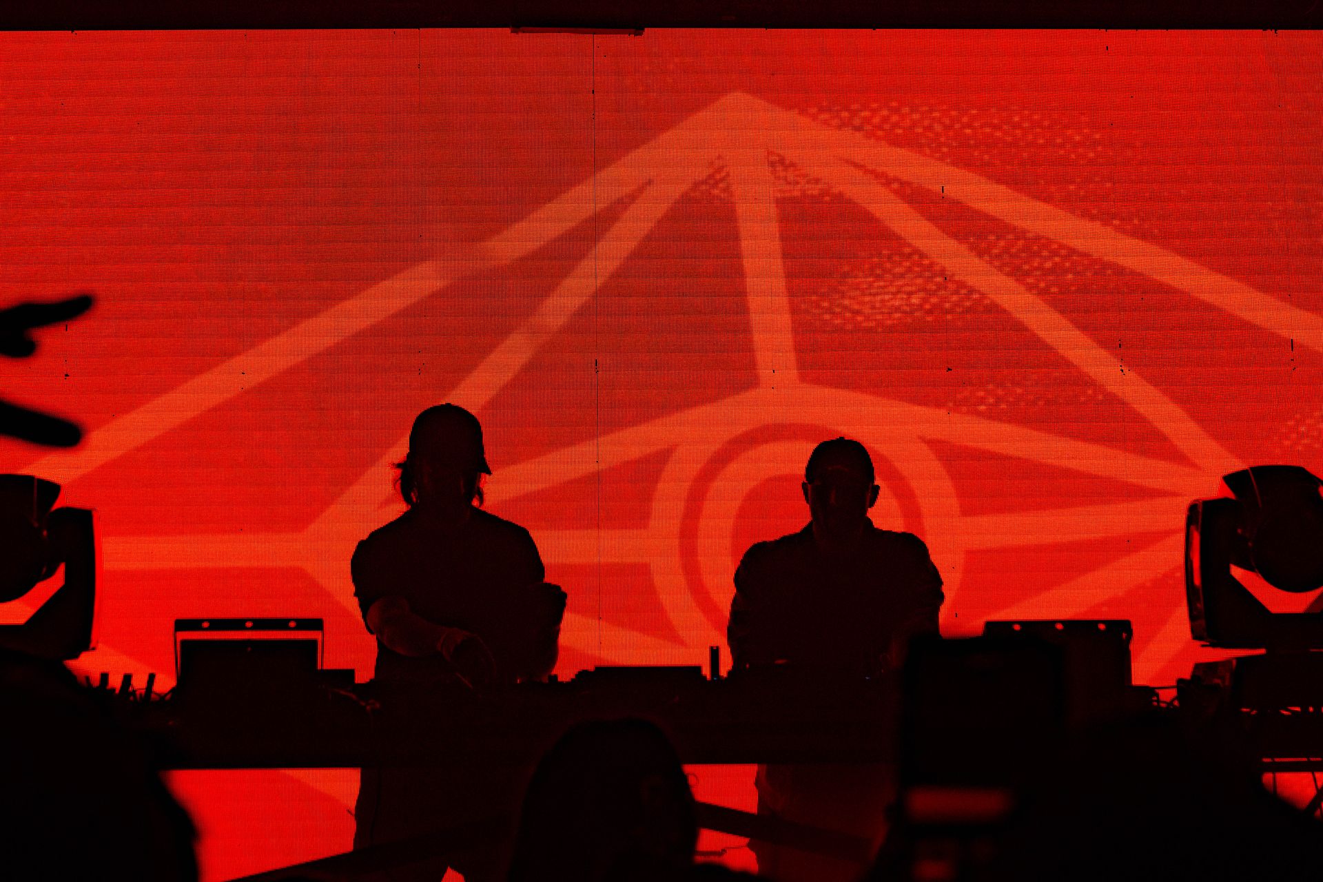 Two men are standing in front of a large screen in a dark room.