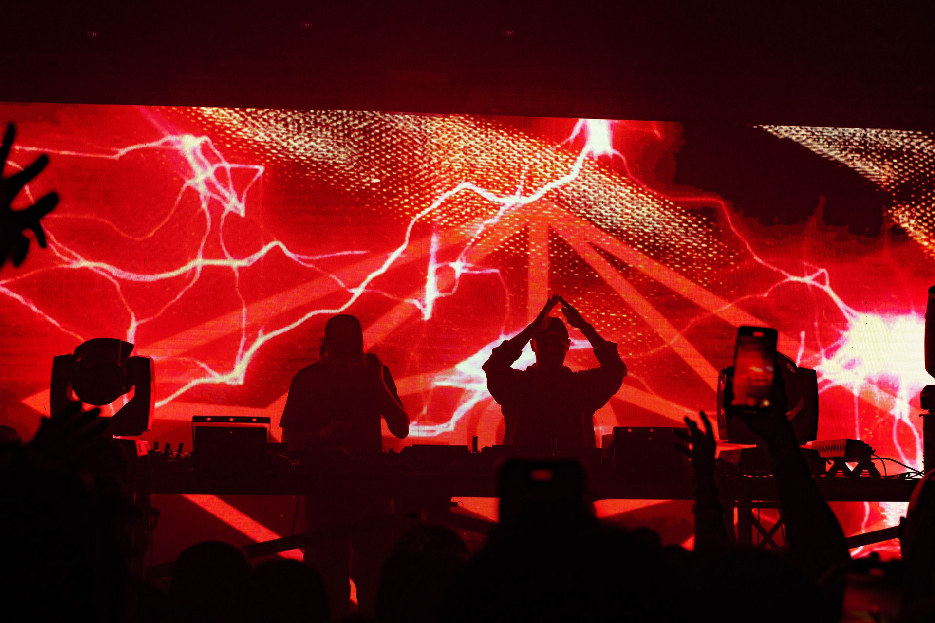 A group of people are standing in front of a large screen with a red lightning bolt on it.