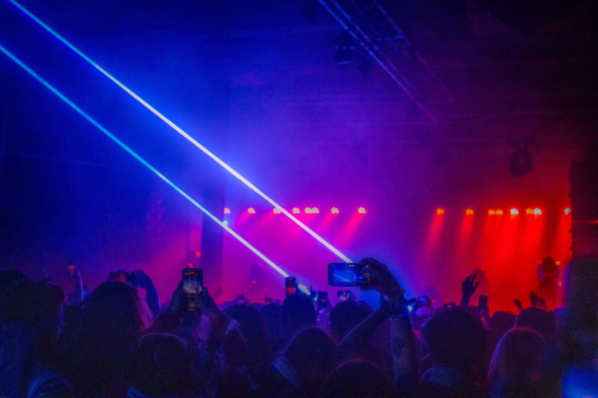 A crowd of people are standing in front of a stage at a concert.