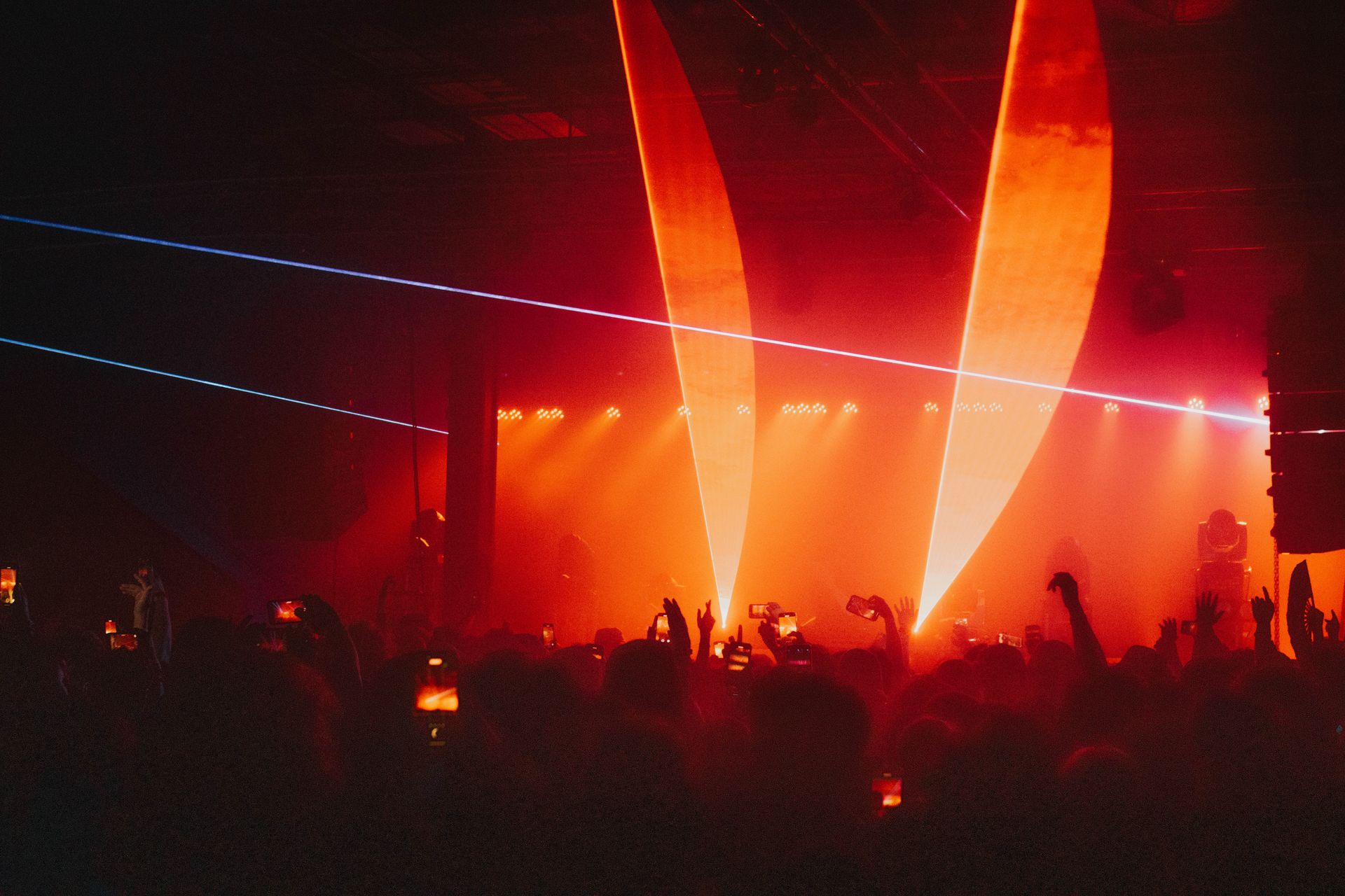 A crowd of people are standing in front of a stage at a concert.