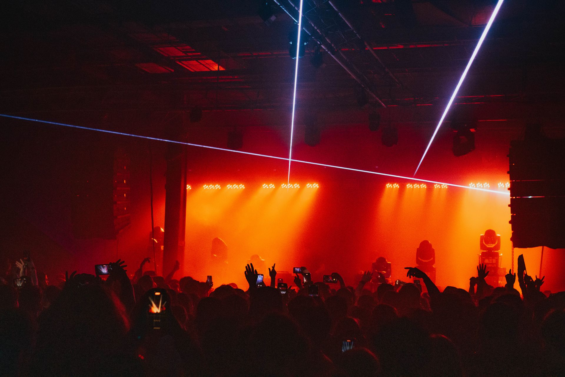 A crowd of people are standing in front of a stage at a concert.