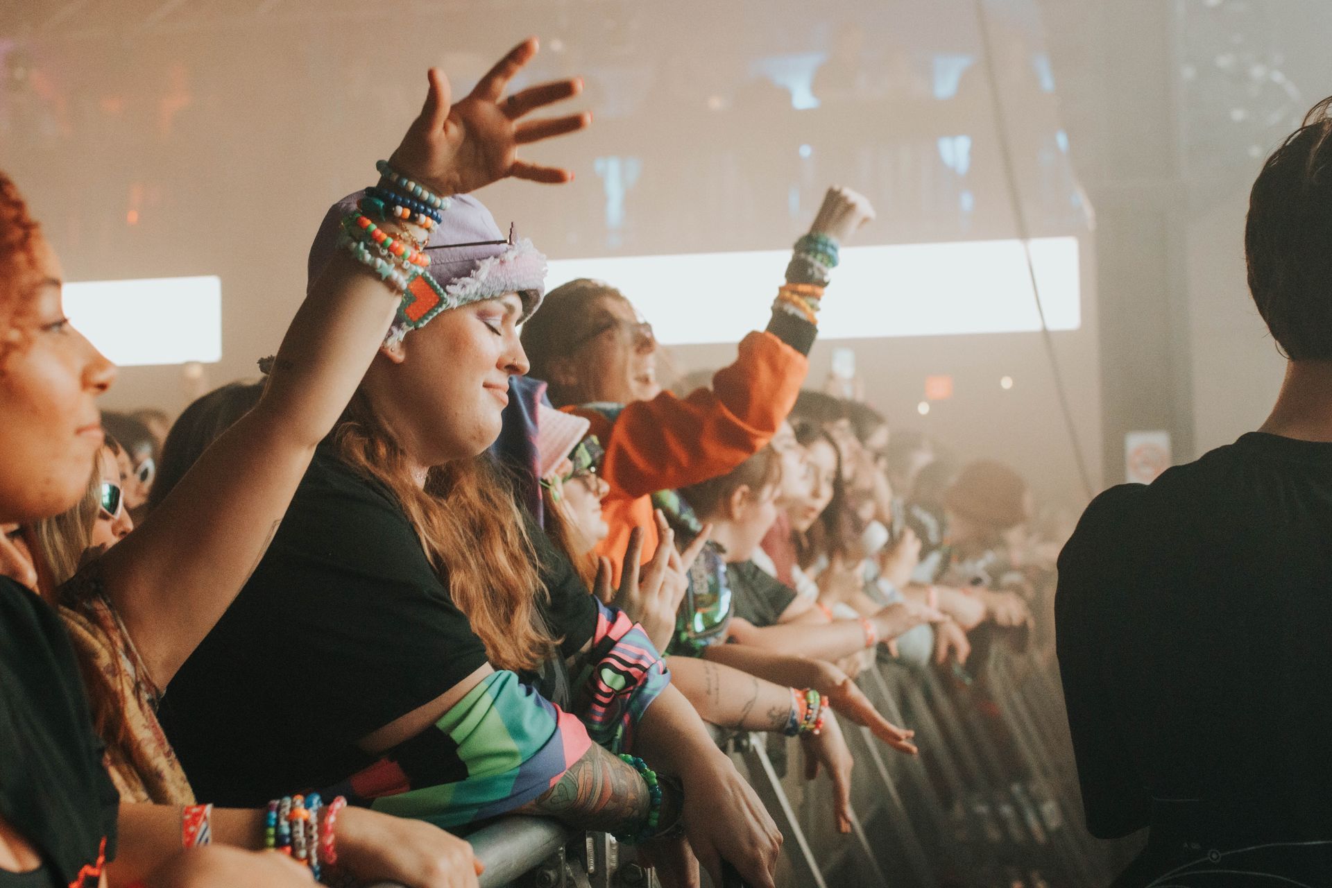A crowd of people at a concert with their hands in the air.
