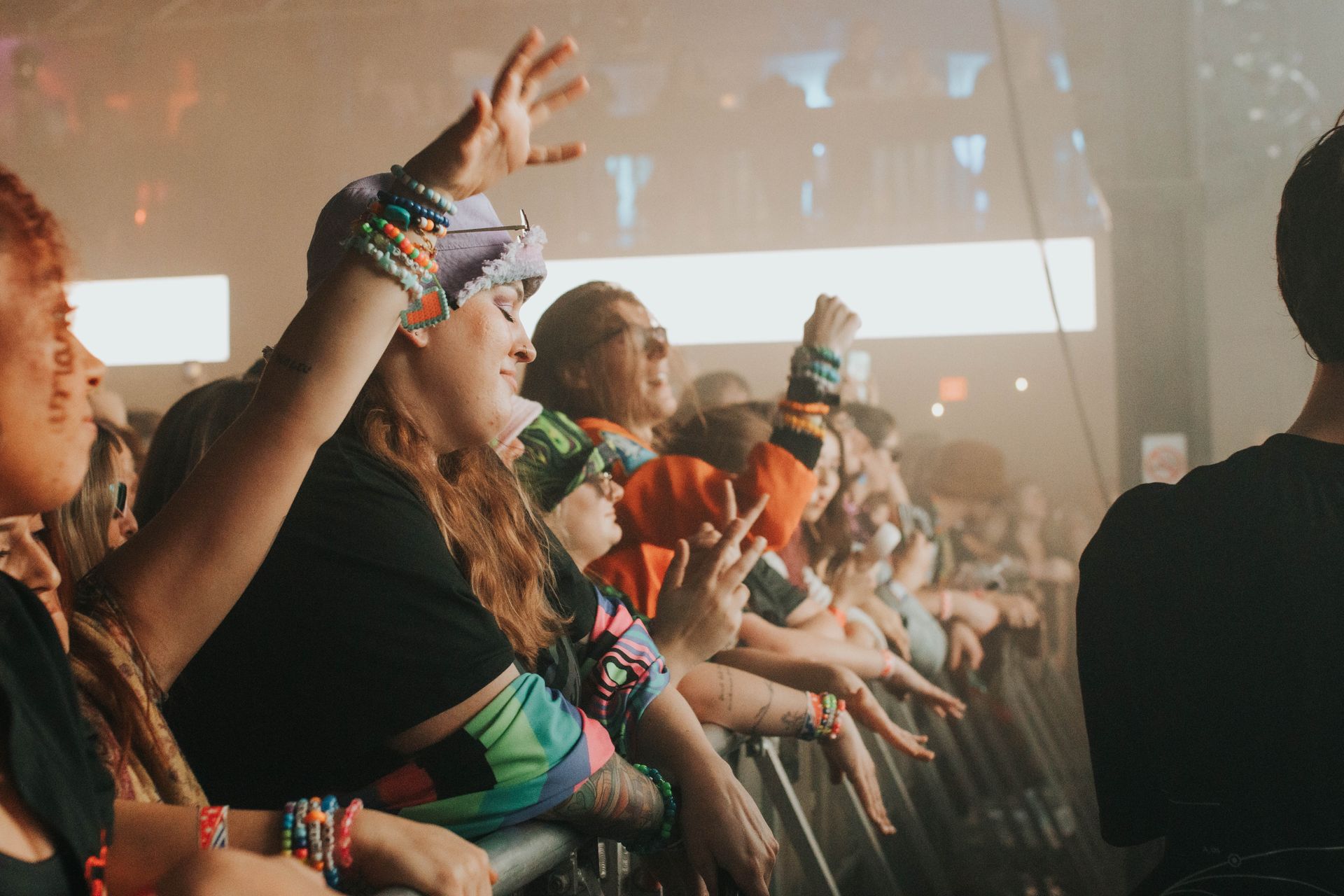 A crowd of people at a concert with their hands in the air.