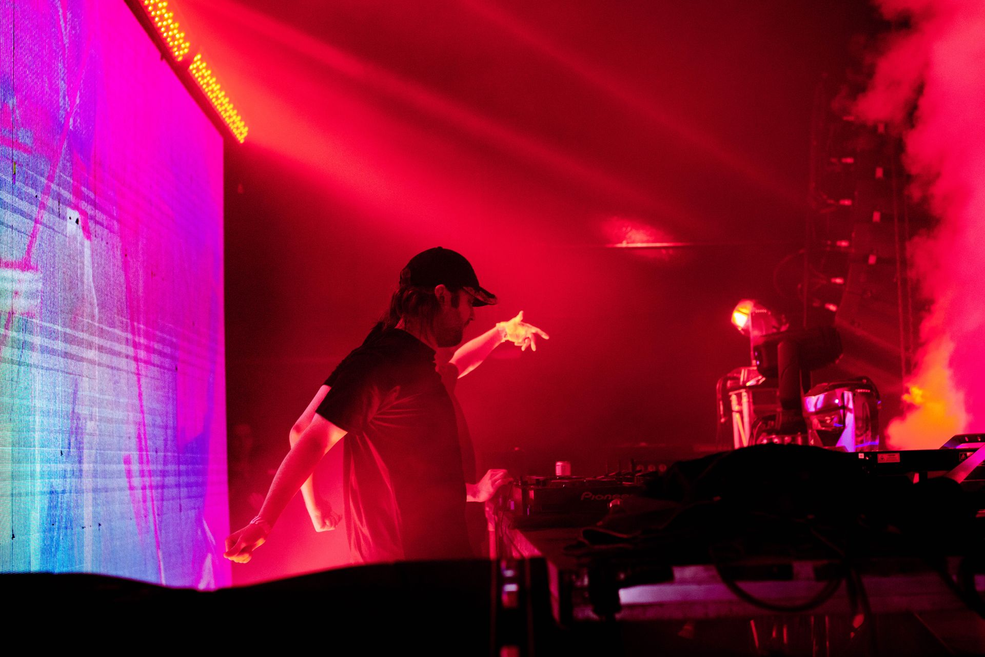 A man is playing a guitar on a stage in front of a large screen.